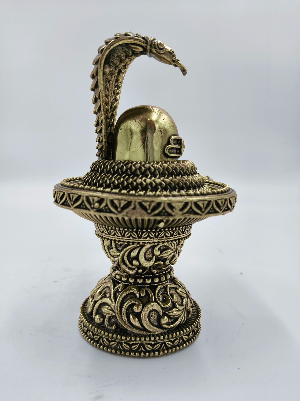 Medium brass Shivalinga sculpture with detailed carvings and a serpent hood