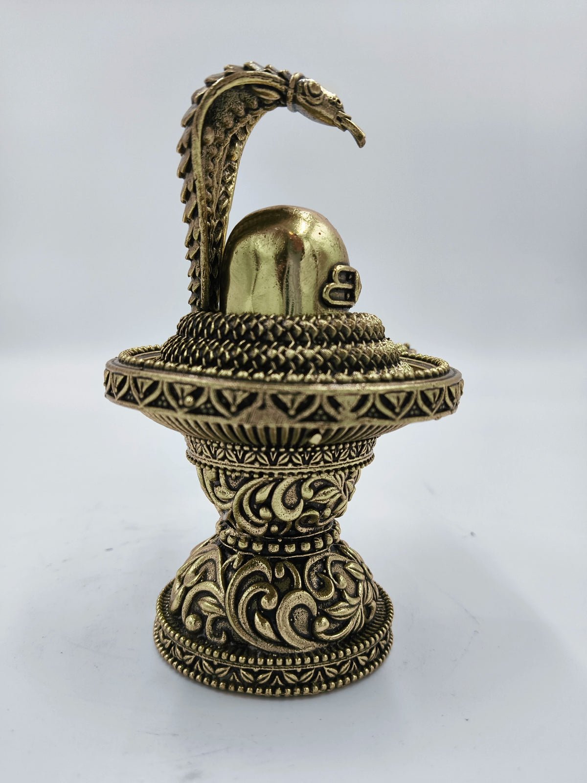 Medium brass Shivalinga sculpture with detailed carvings and a serpent hood