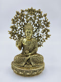 Small brass Buddha figurine seated in meditation with intricate tree design backdrop