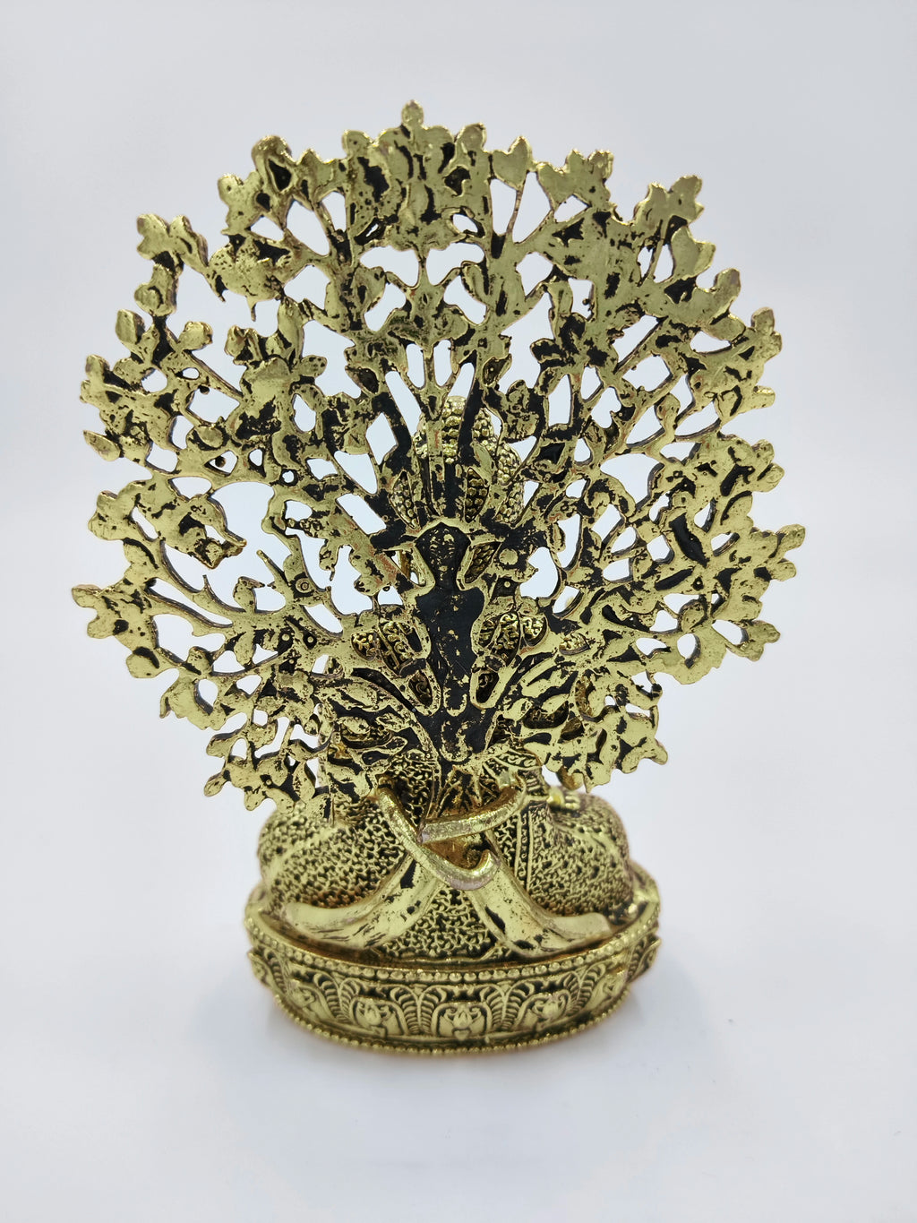 small brass Buddha figurine seated with detailed ornamental backdrop