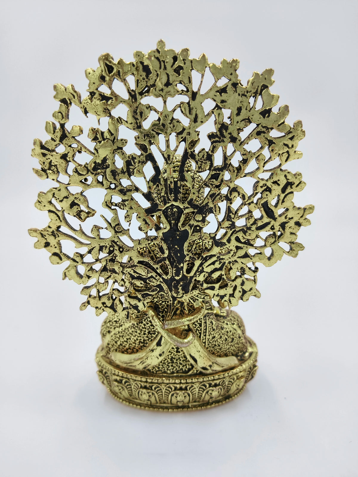 small brass Buddha figurine seated with detailed ornamental backdrop
