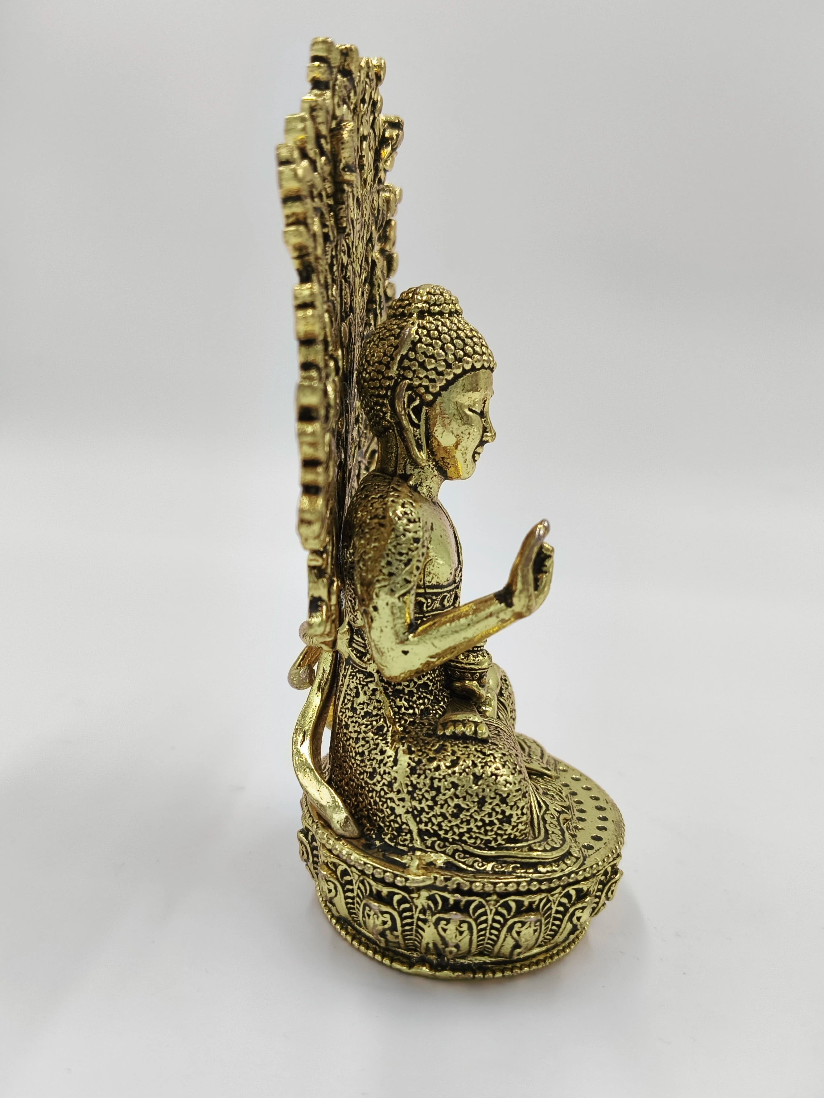 Side view of small brass Buddha sculpture seated on decorative base