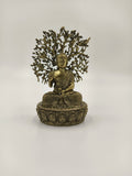 Small brass Buddha statue seated with detailed lotus pedestal and tree backdrop