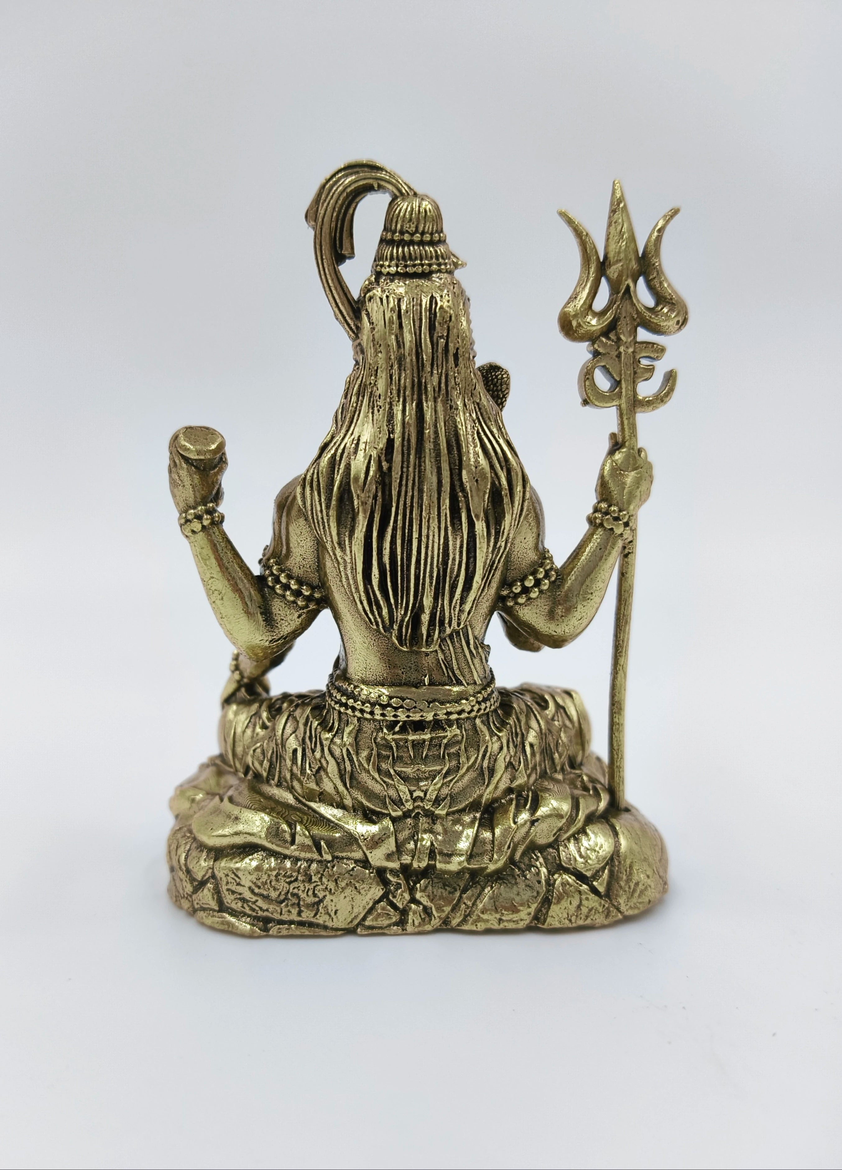 Back view of small brass Mahadeva (Shiva) sitting with trident sculpture