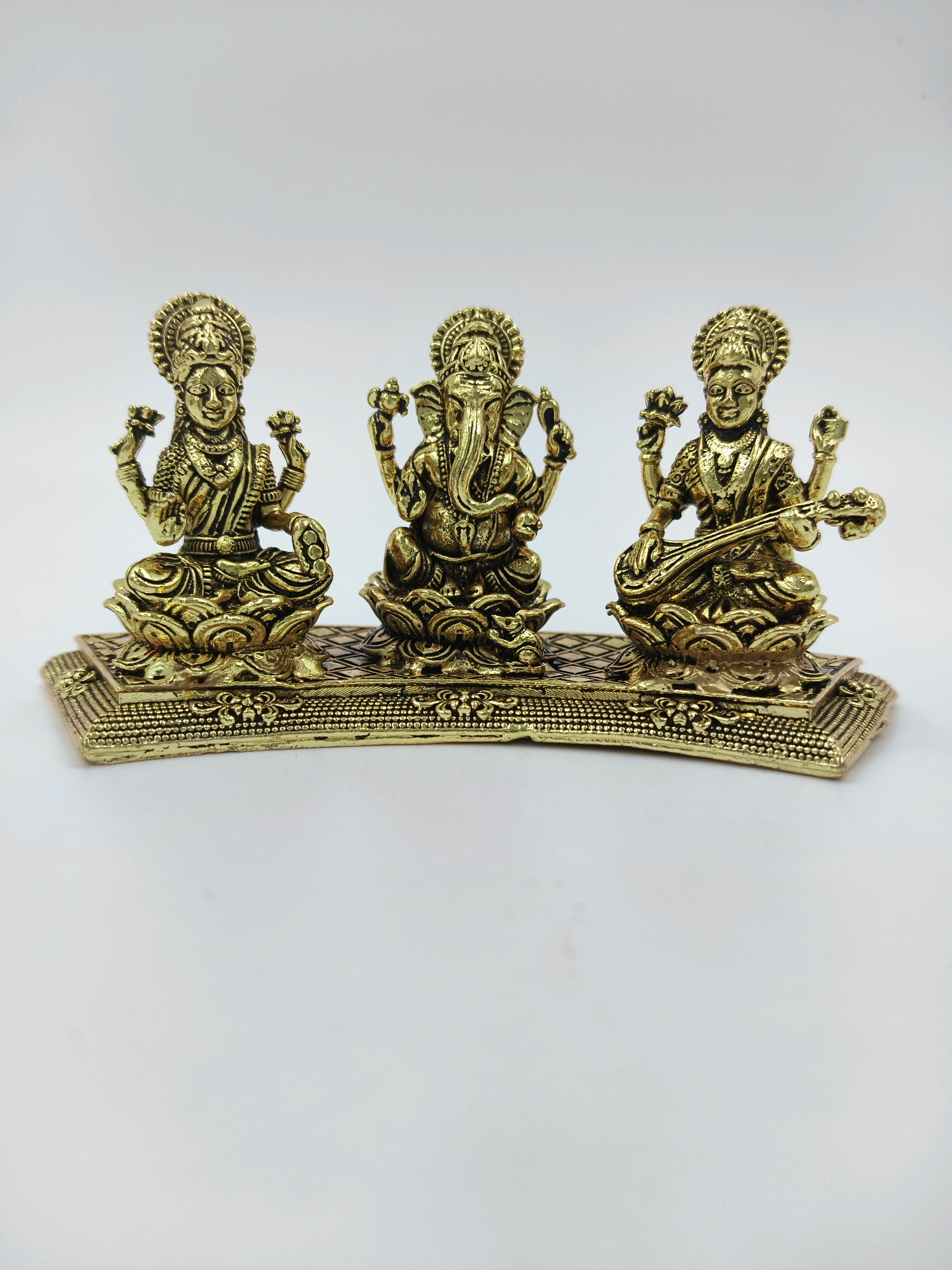 Mini brass statue featuring Lakshmi, Ganesh, and Saraswathi seated on a decorative base