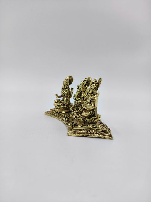 Mini brass statue depicting deities Lakshmi, Ganesh, and Saraswathi seated on ornate base