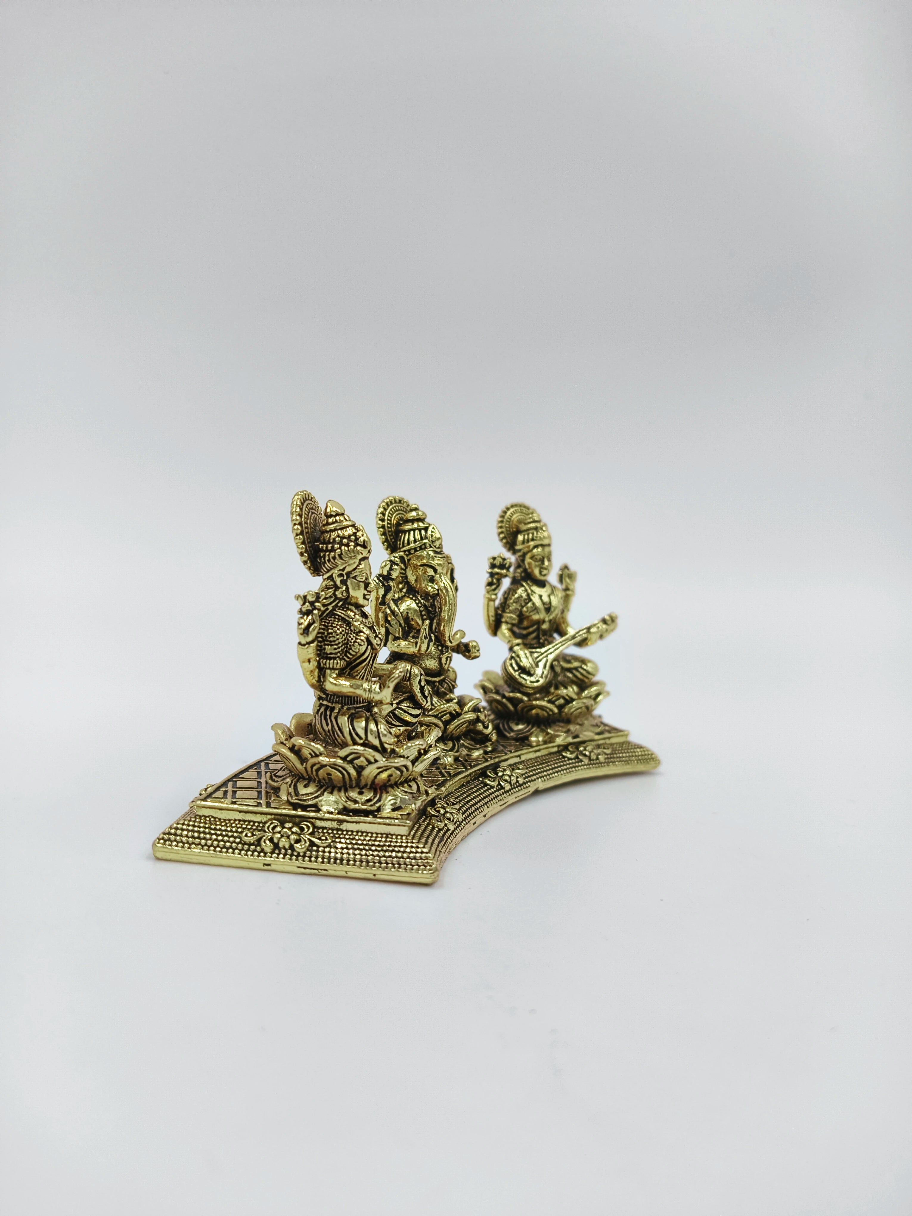 Mini brass statue of Lakshmi, Ganesh, and Saraswathi on a curved base, side view