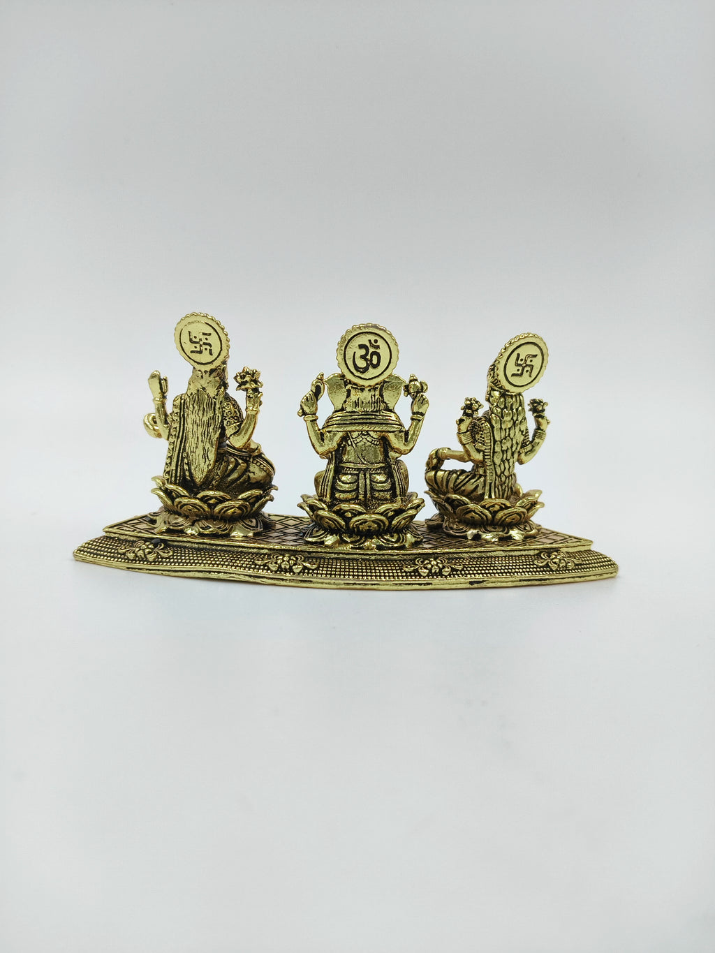 Mini brass statue featuring deities Lakshmi, Ganesh, and Saraswathi from back view