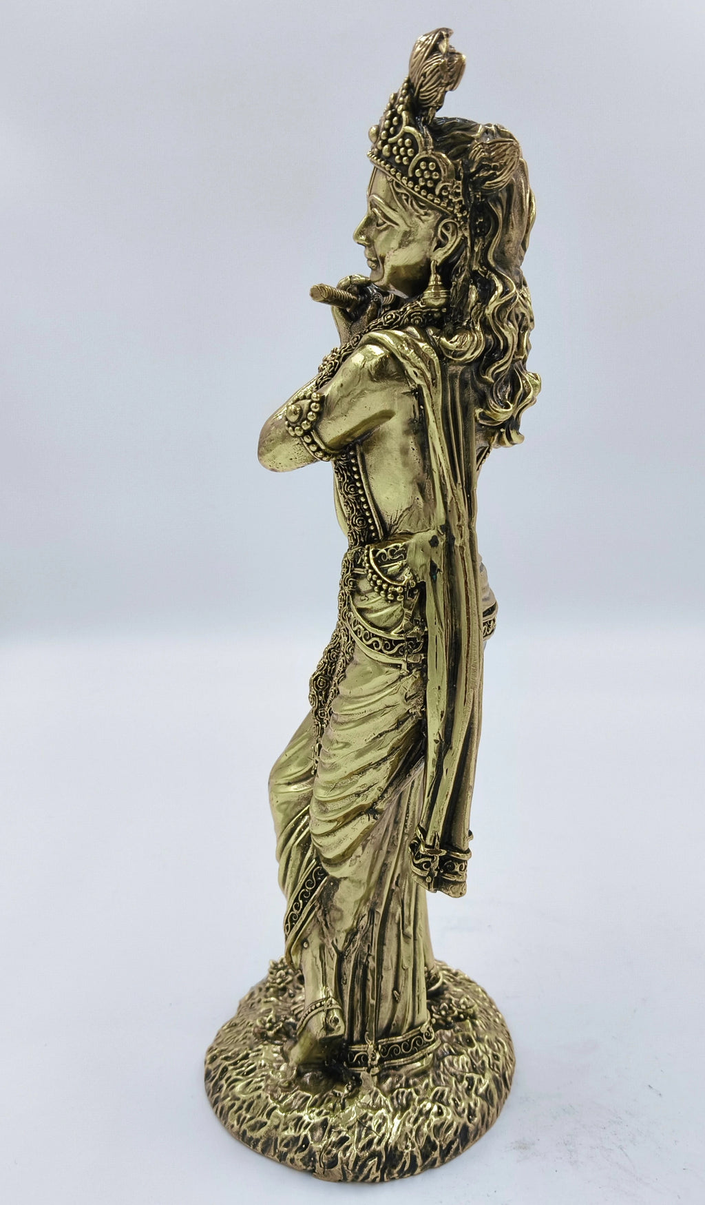 Side view of large brass Krishna statue playing flute with detailed garment