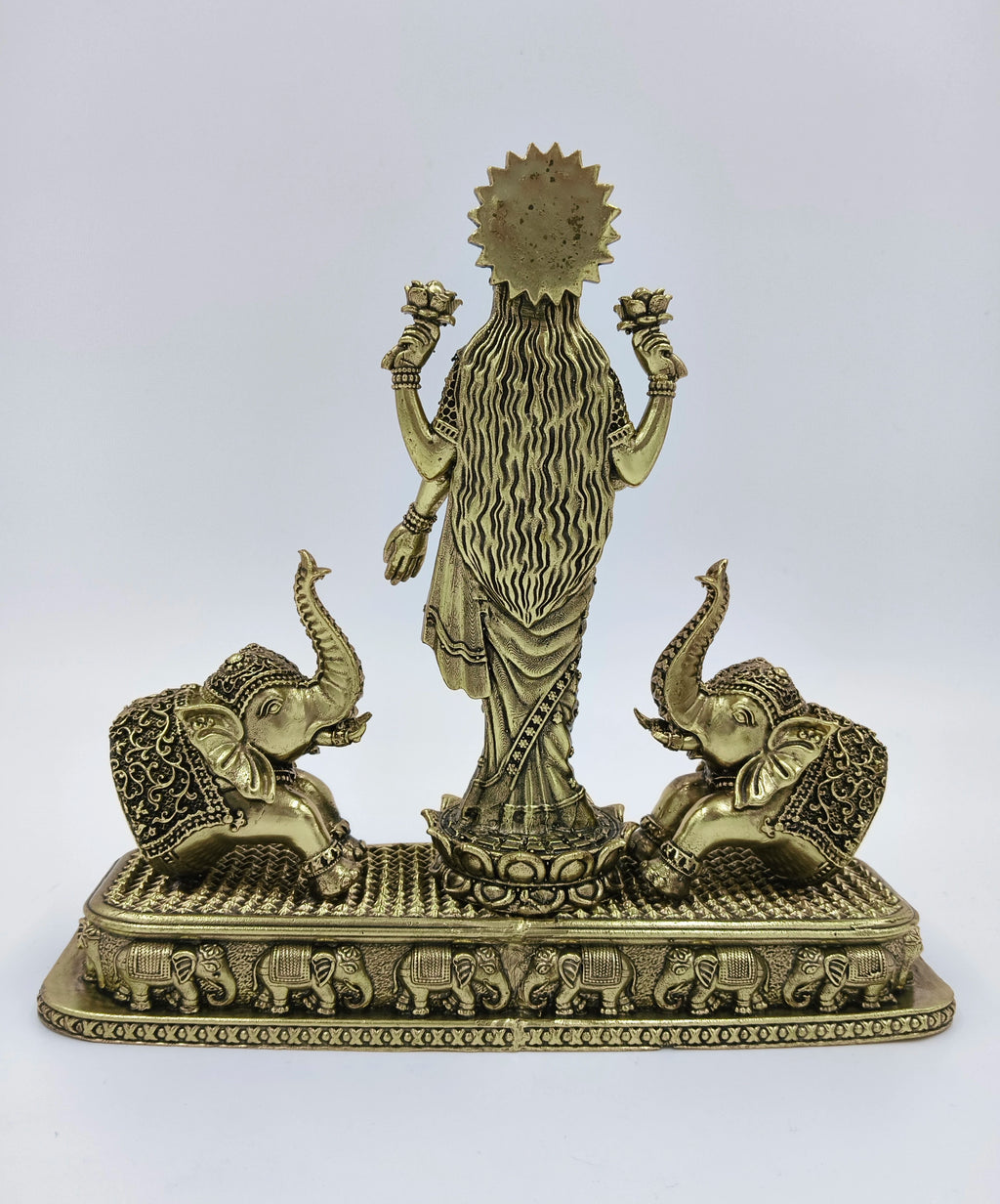 Back view of brass standing Gajalakshmi statue with two elephants on a decorated base