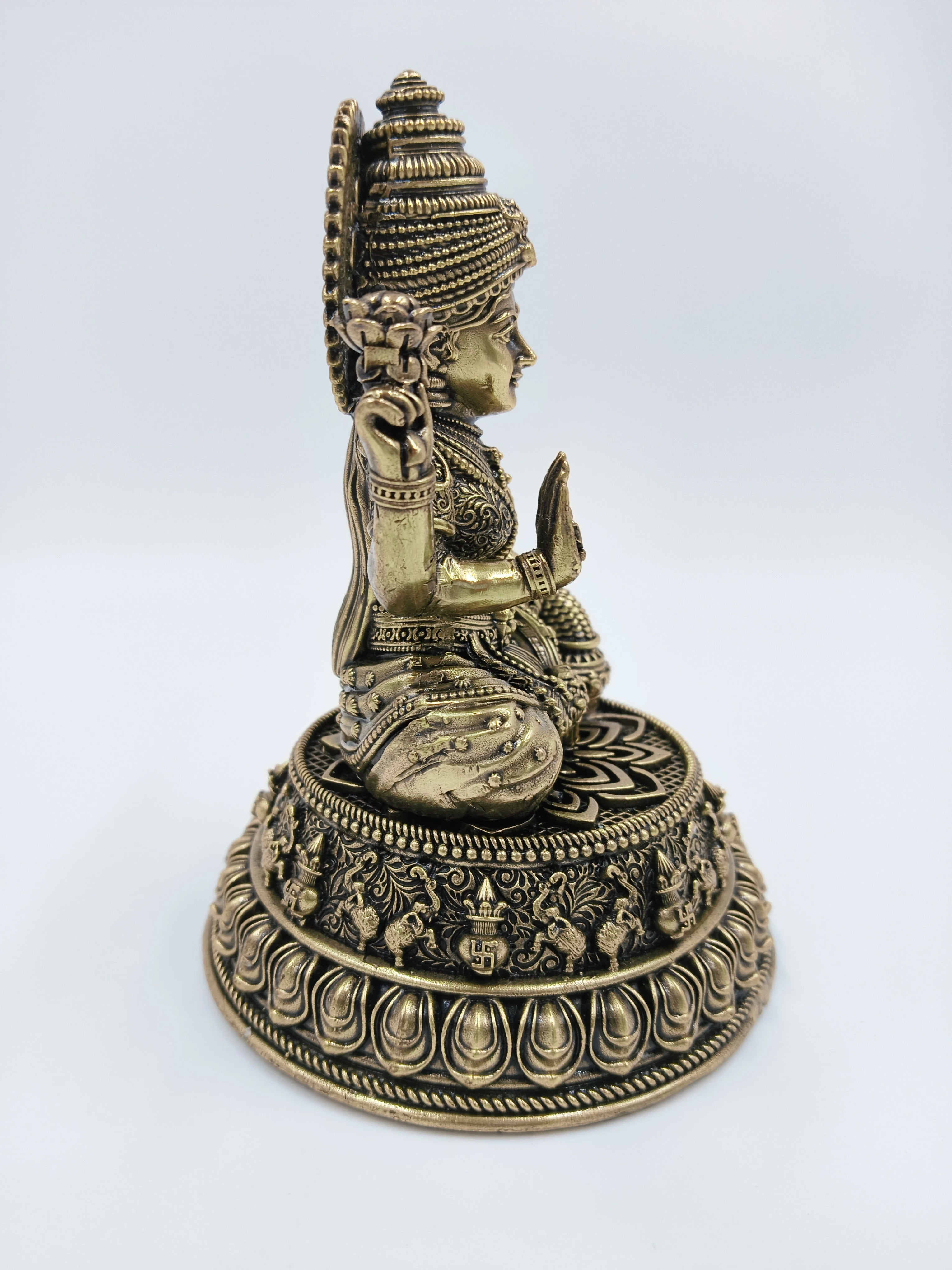 Side view of a medium-sized brass Lakshmi Padmini sculpture sitting on an ornate base