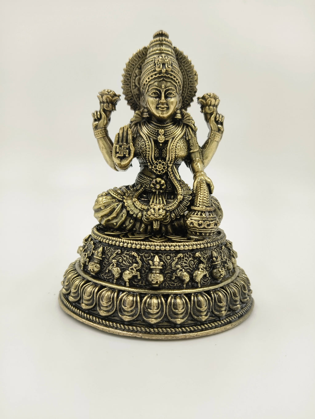 Brass figurine of deity Lakshmi seated on decorative base, front view
