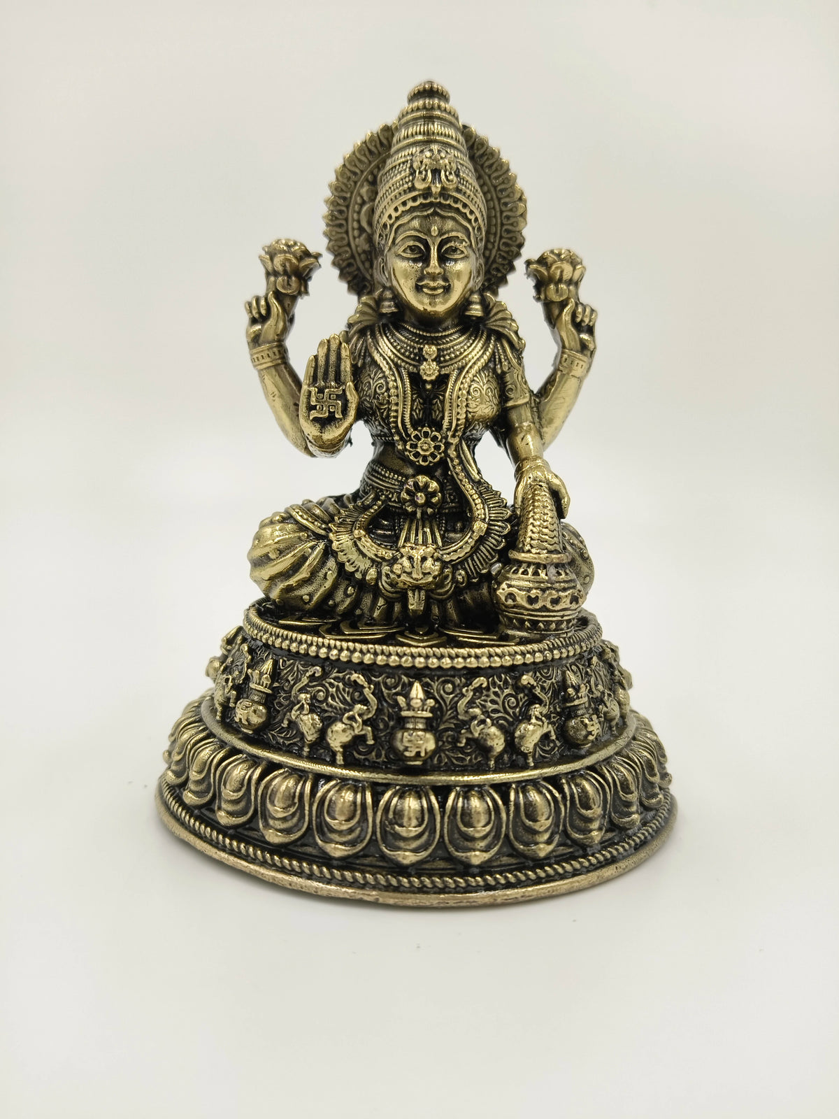 Brass figurine of deity Lakshmi seated on decorative base, front view