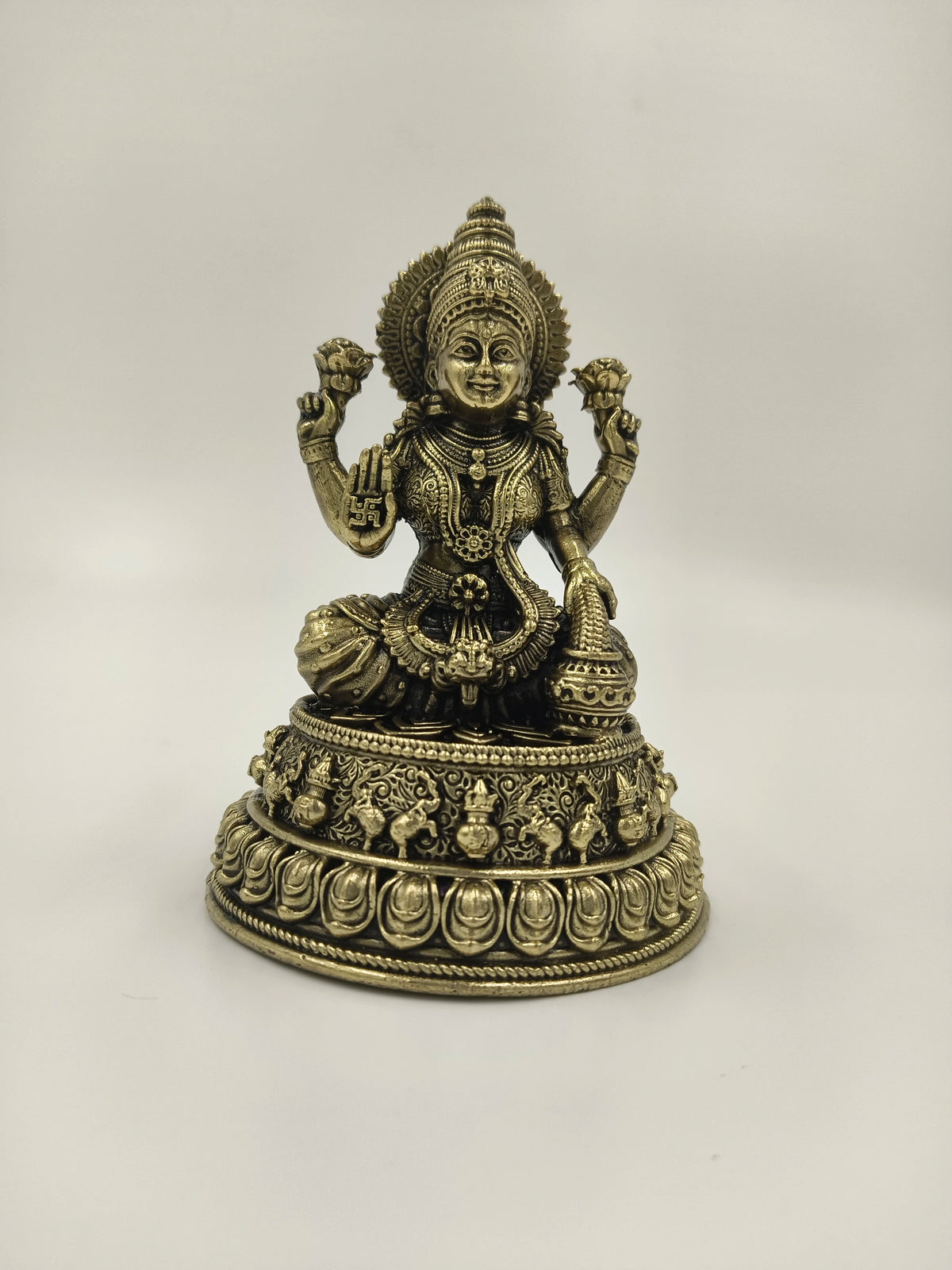 Small brass statue of Lakshmi goddess seated on lotus pedestal with intricate detailing