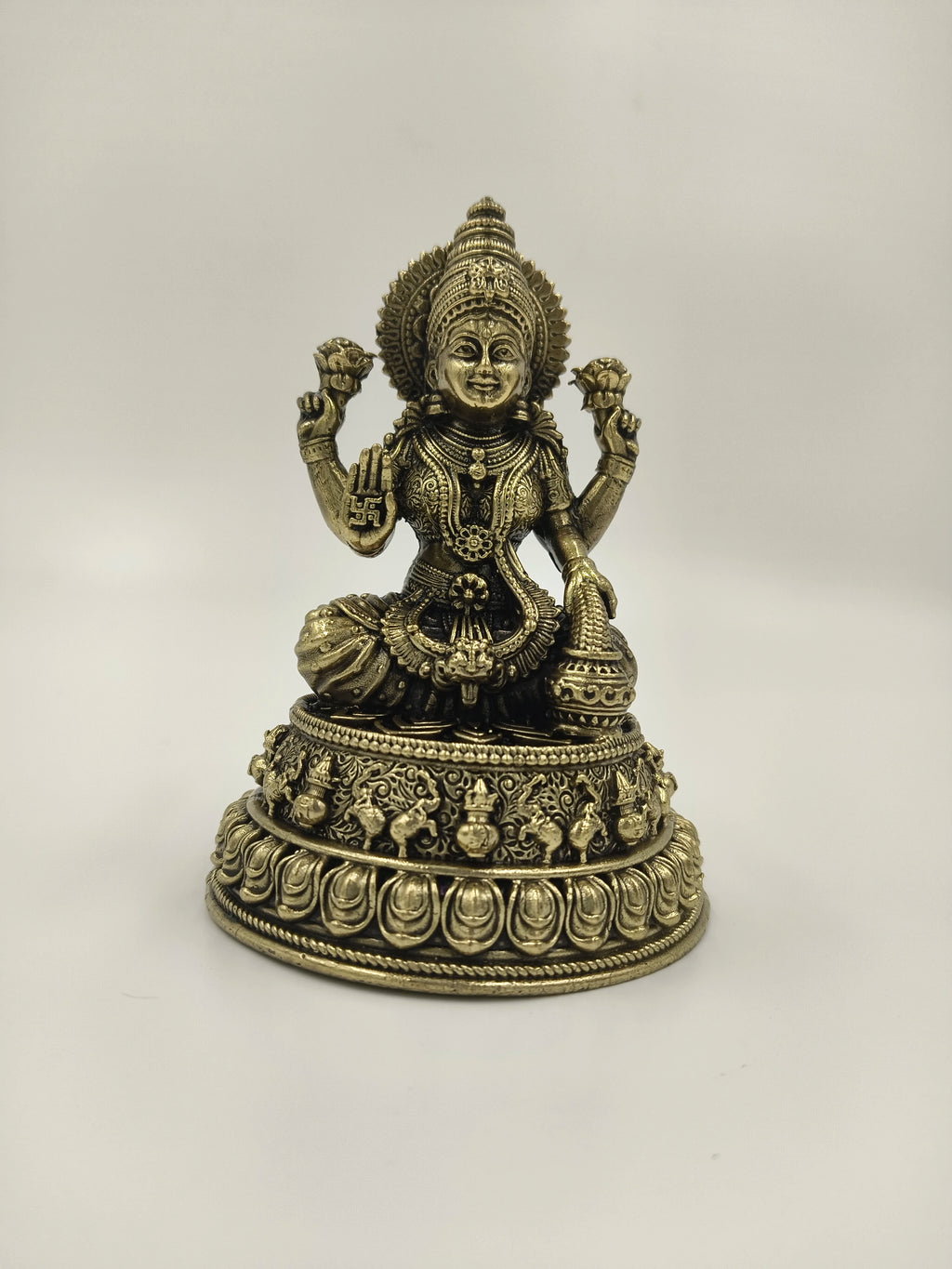 Small brass statue of Lakshmi goddess seated on lotus pedestal with intricate detailing
