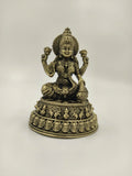 Small brass statue of Lakshmi goddess seated on lotus pedestal with intricate detailing