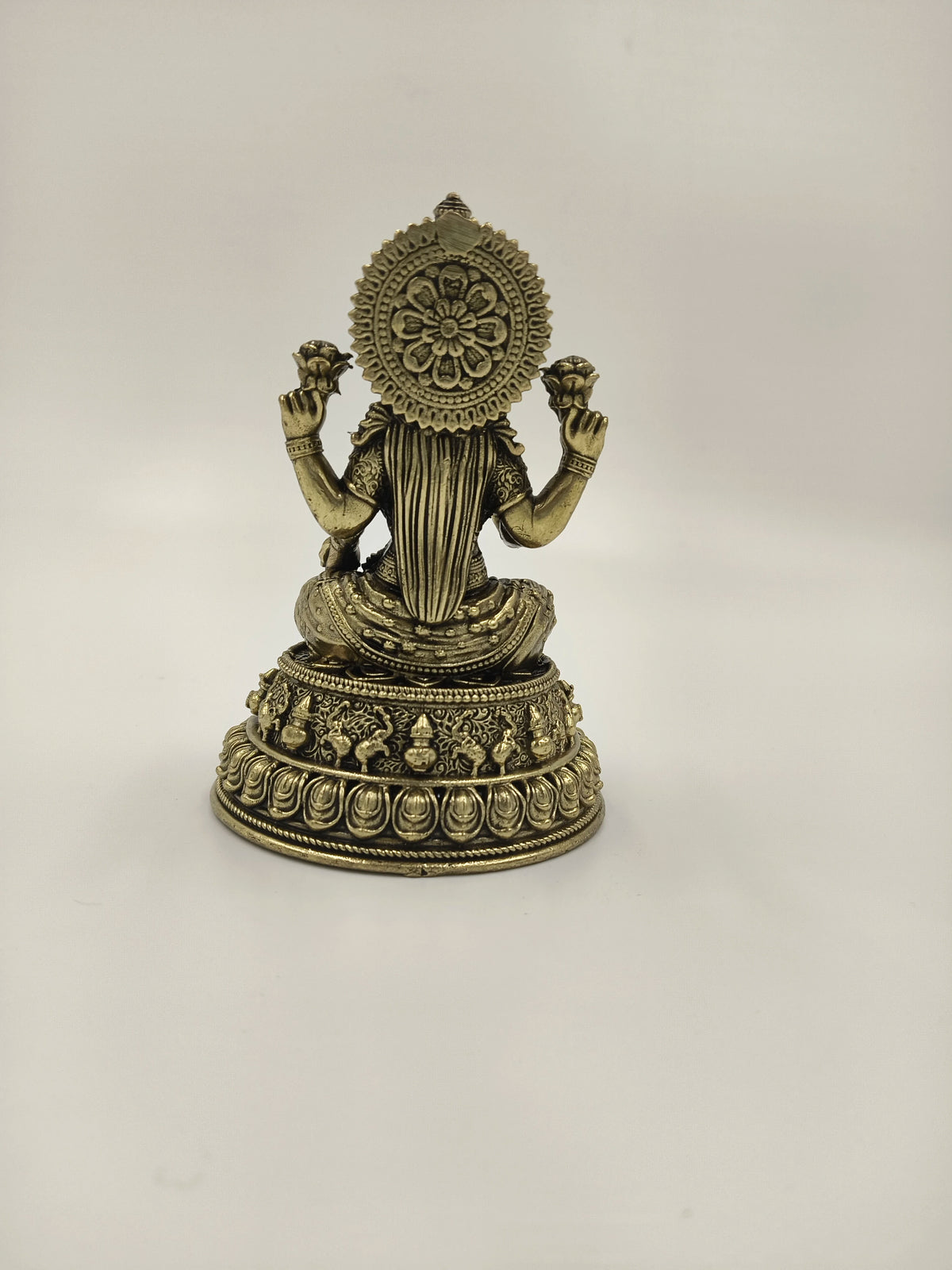Back view of a small brass Padmini statue depicting deity Lakshmi holding lotus flowers