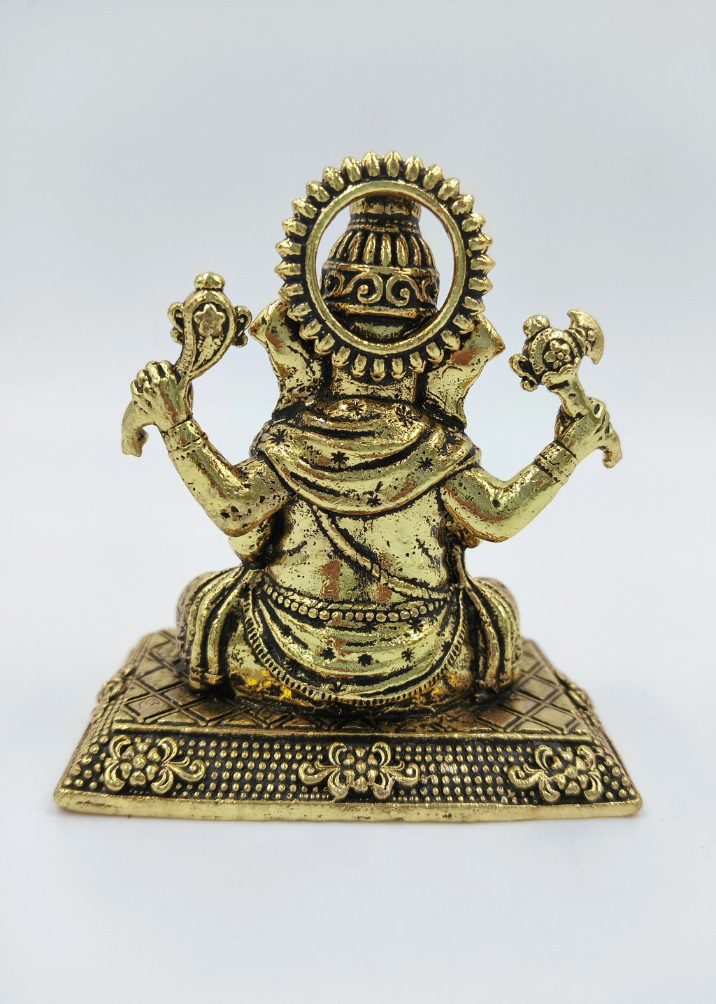 Back view of small brass Ganesh statue seated on decorated base