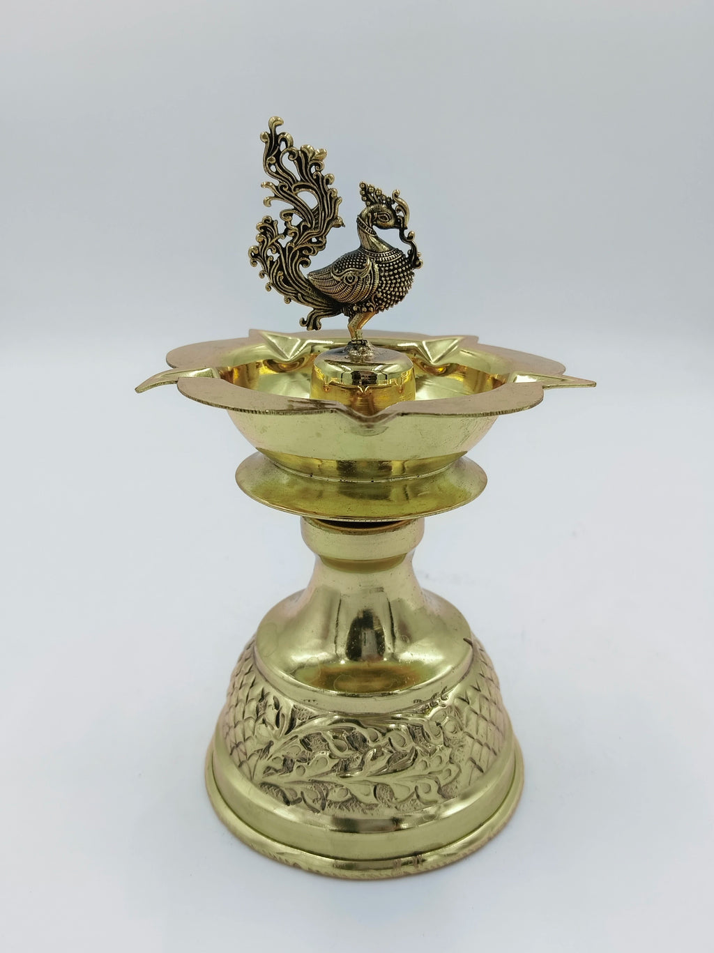 Large brass diya oil lamp with detailed peacock figure and engraved base