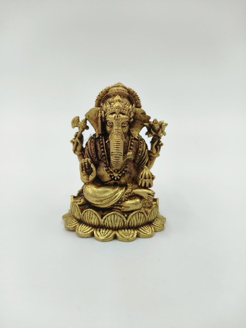 Mini brass Ganesh idol seated on lotus base with detailed ornaments