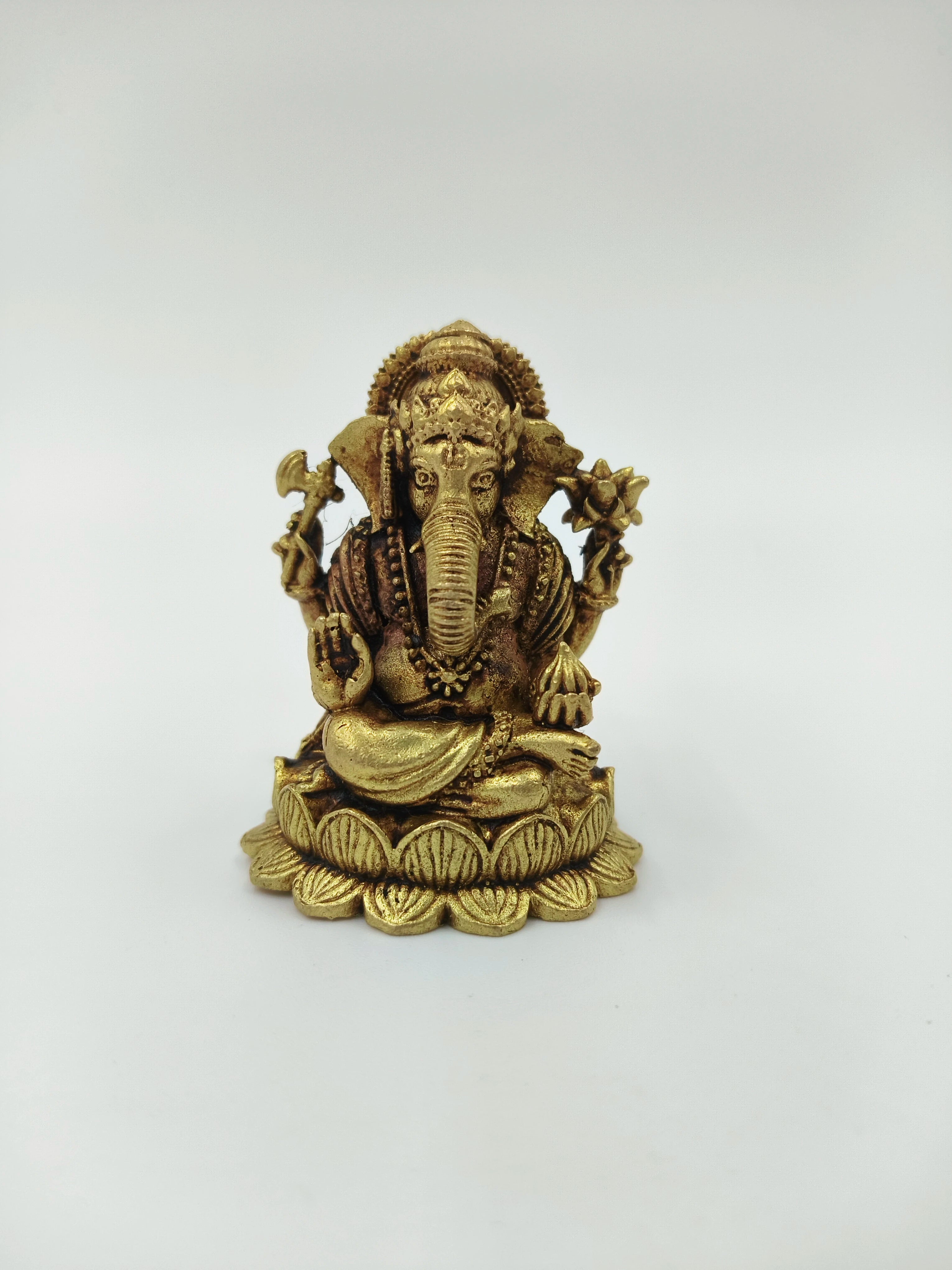 Mini brass Ganesh idol seated on lotus base with detailed ornaments