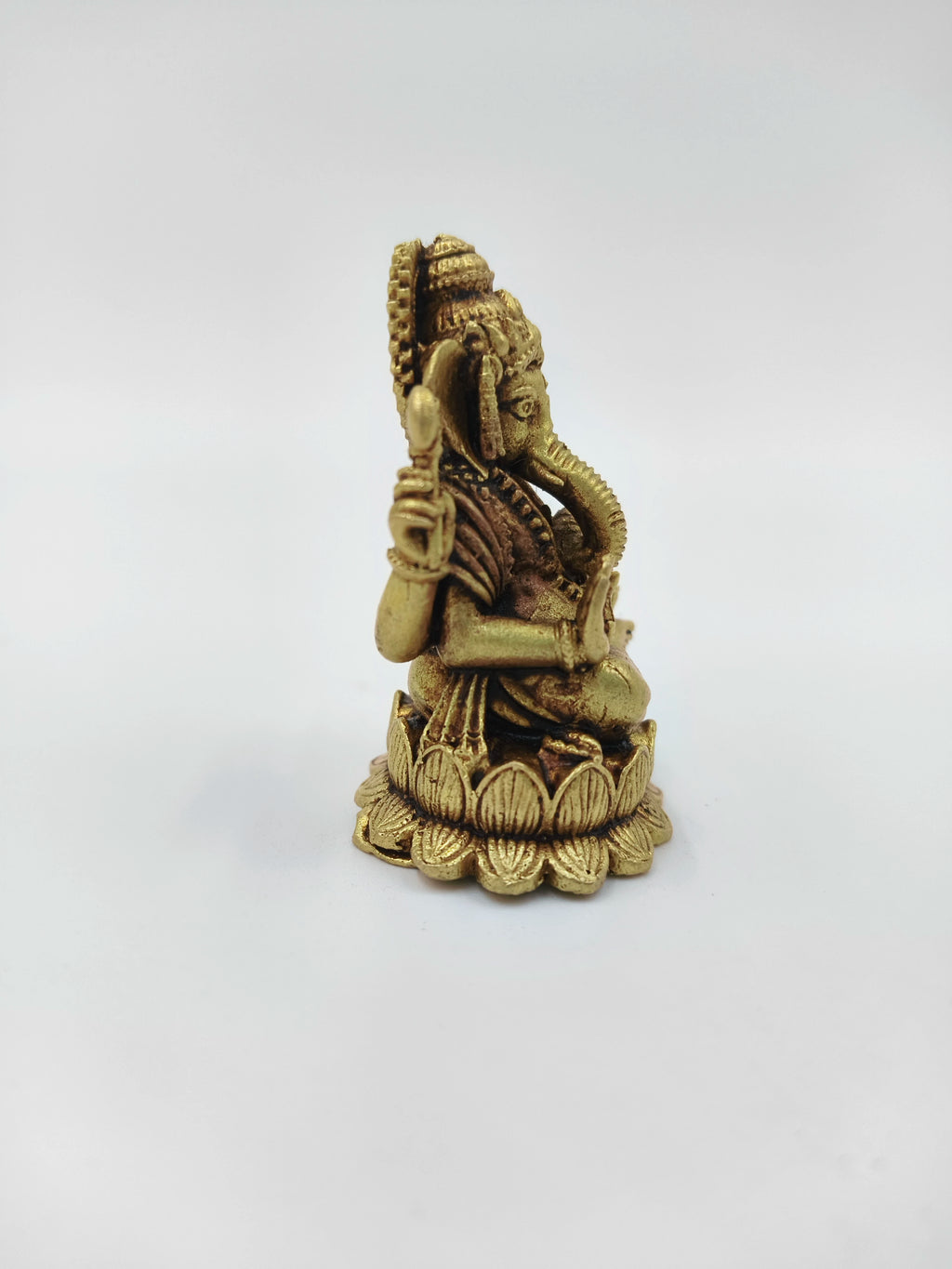 Side view of mini brass Ganesh idol sitting on lotus base