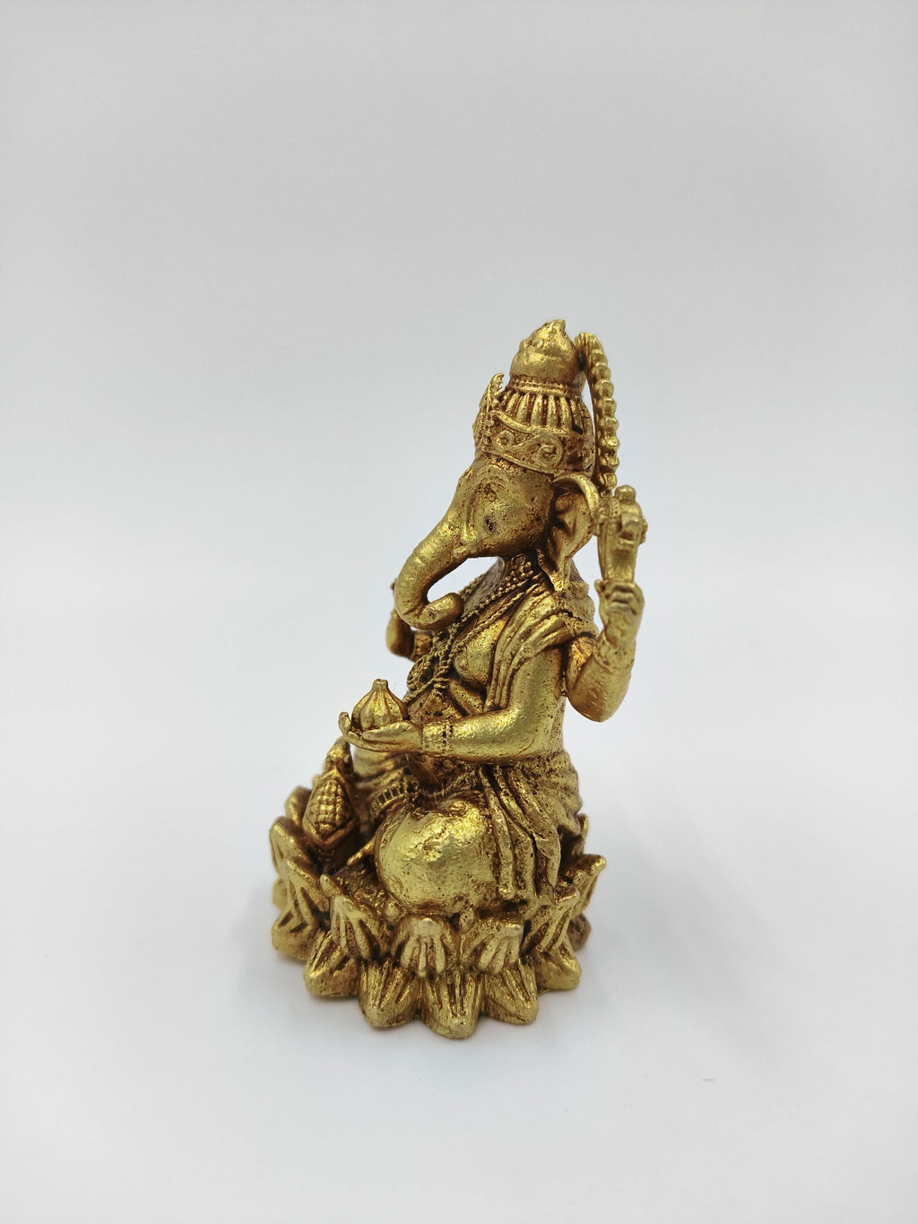 Small brass statue of Vakratunda Ganesh sitting on a lotus base side view