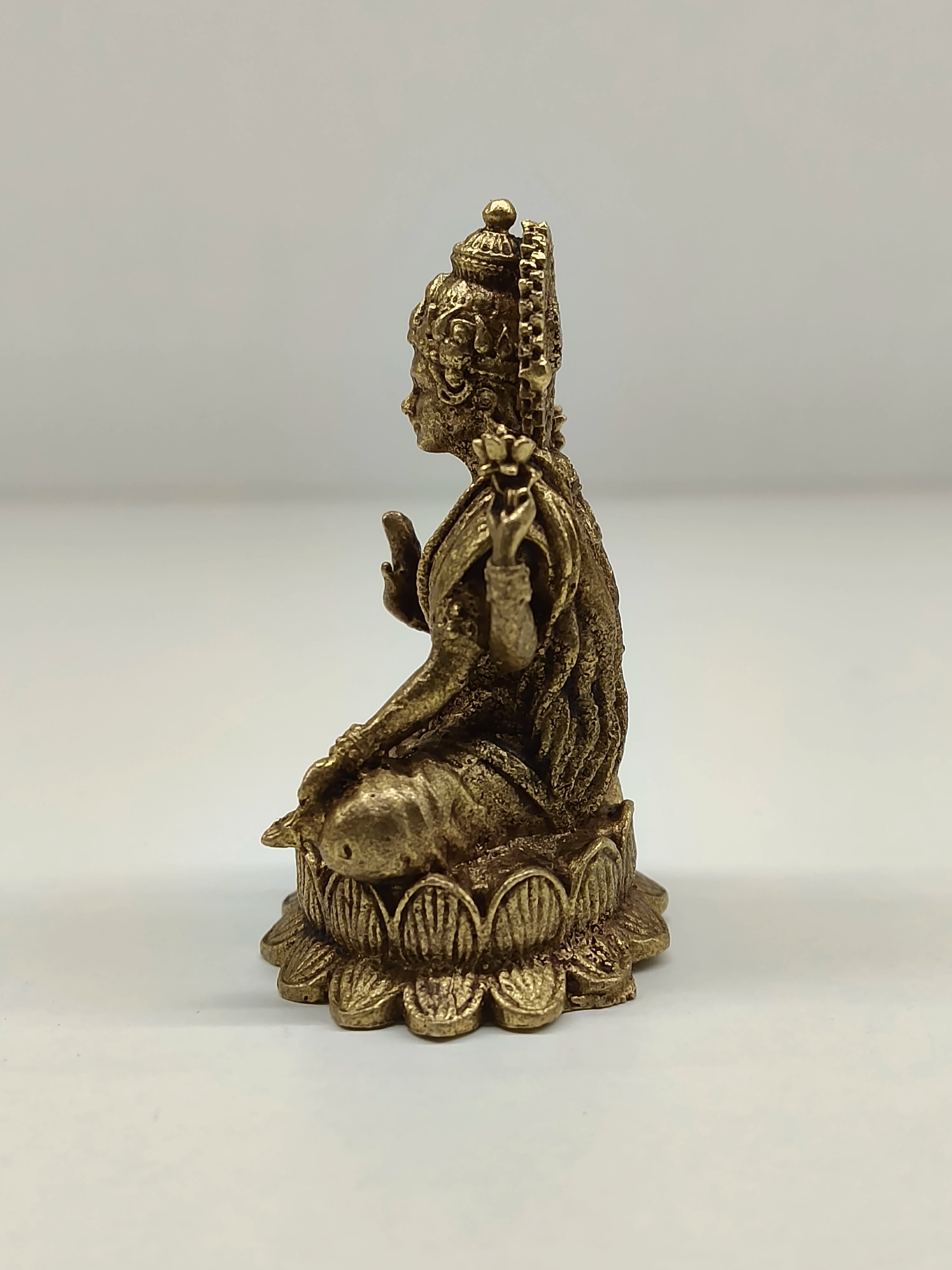 Side view of a mini brass Lakshmi idol seated on lotus base