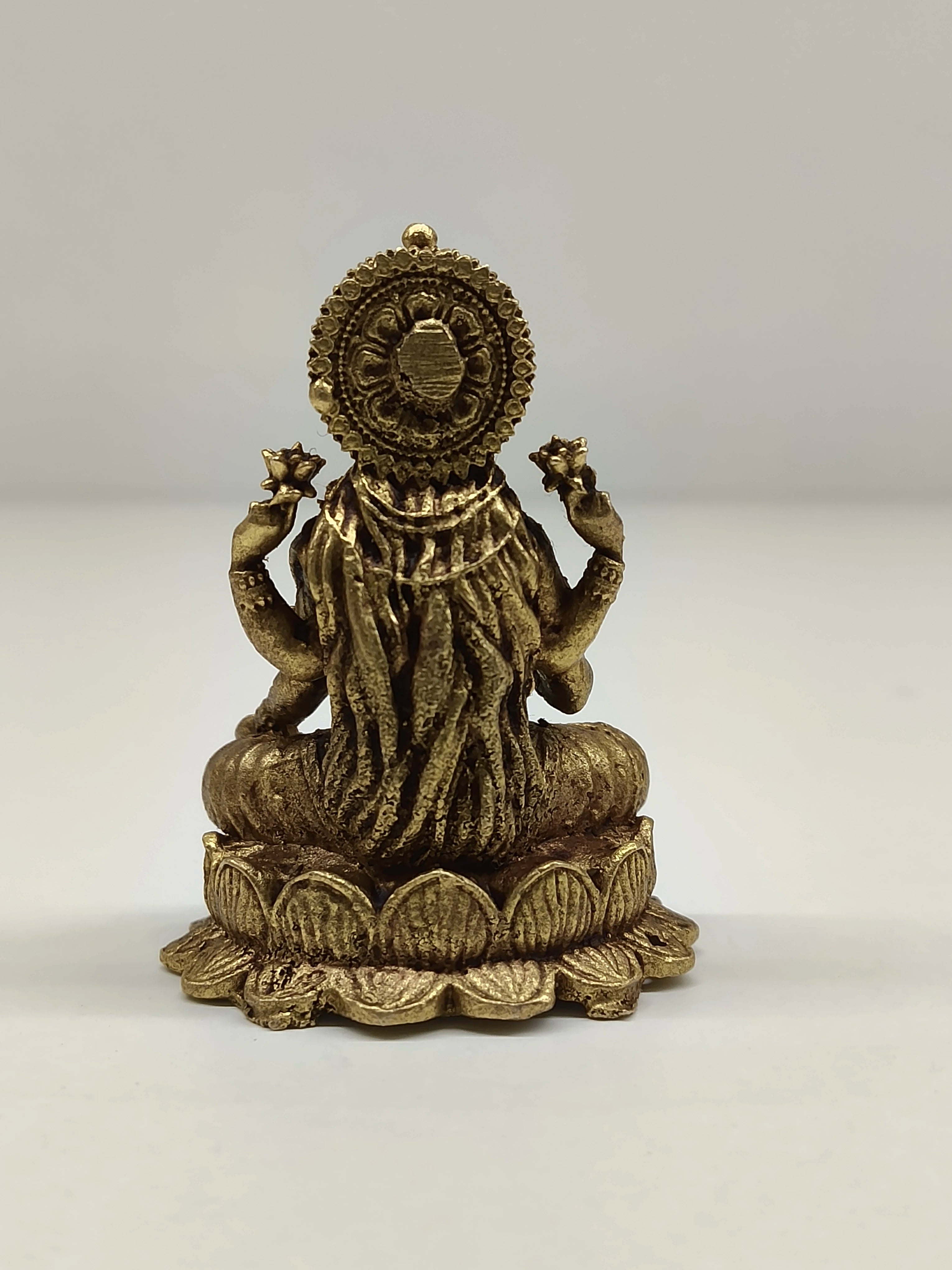 Back view of a small brass Lakshmi idol seated on lotus pedestal