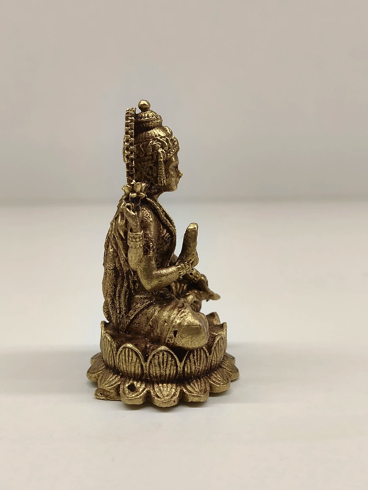 Side view of mini brass Lakshmi idol seated on lotus base