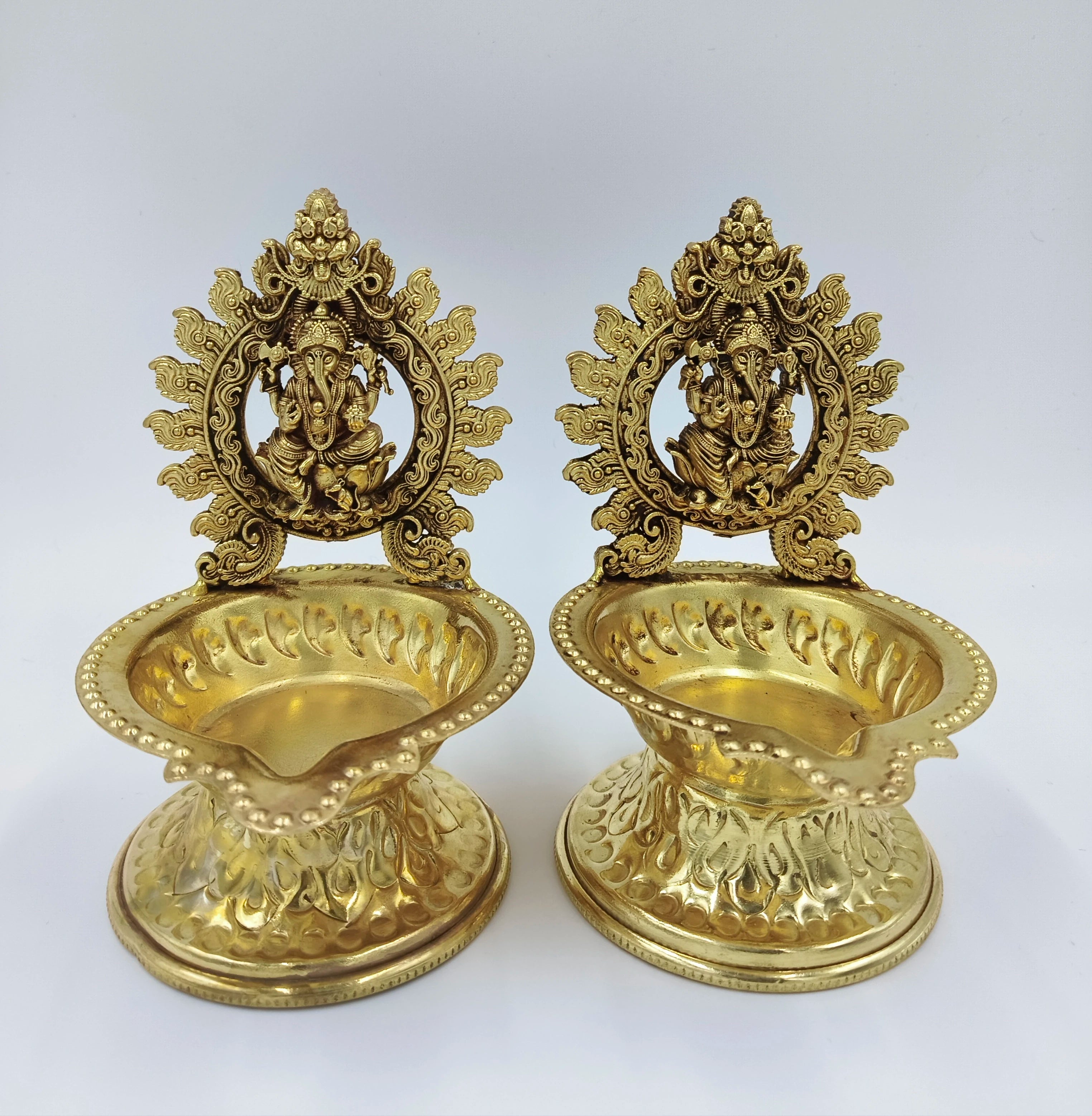 Pair of brass lamps with decorative Ganesh figurines and floral patterns