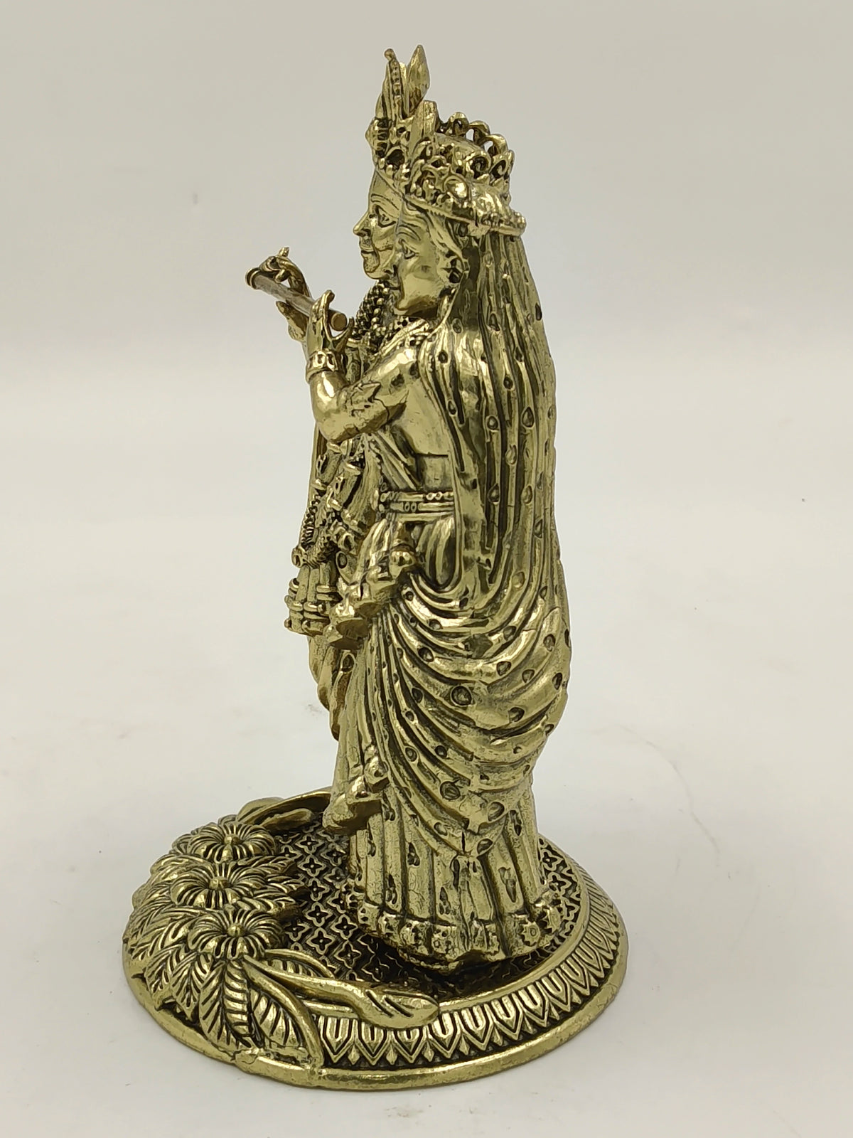 Side view of brass sculpture depicting Radhakrishna standing on decorated base
