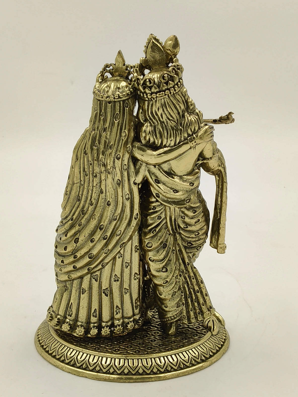 Rear view of brass statue of Radhakrishna standing together on decorated base