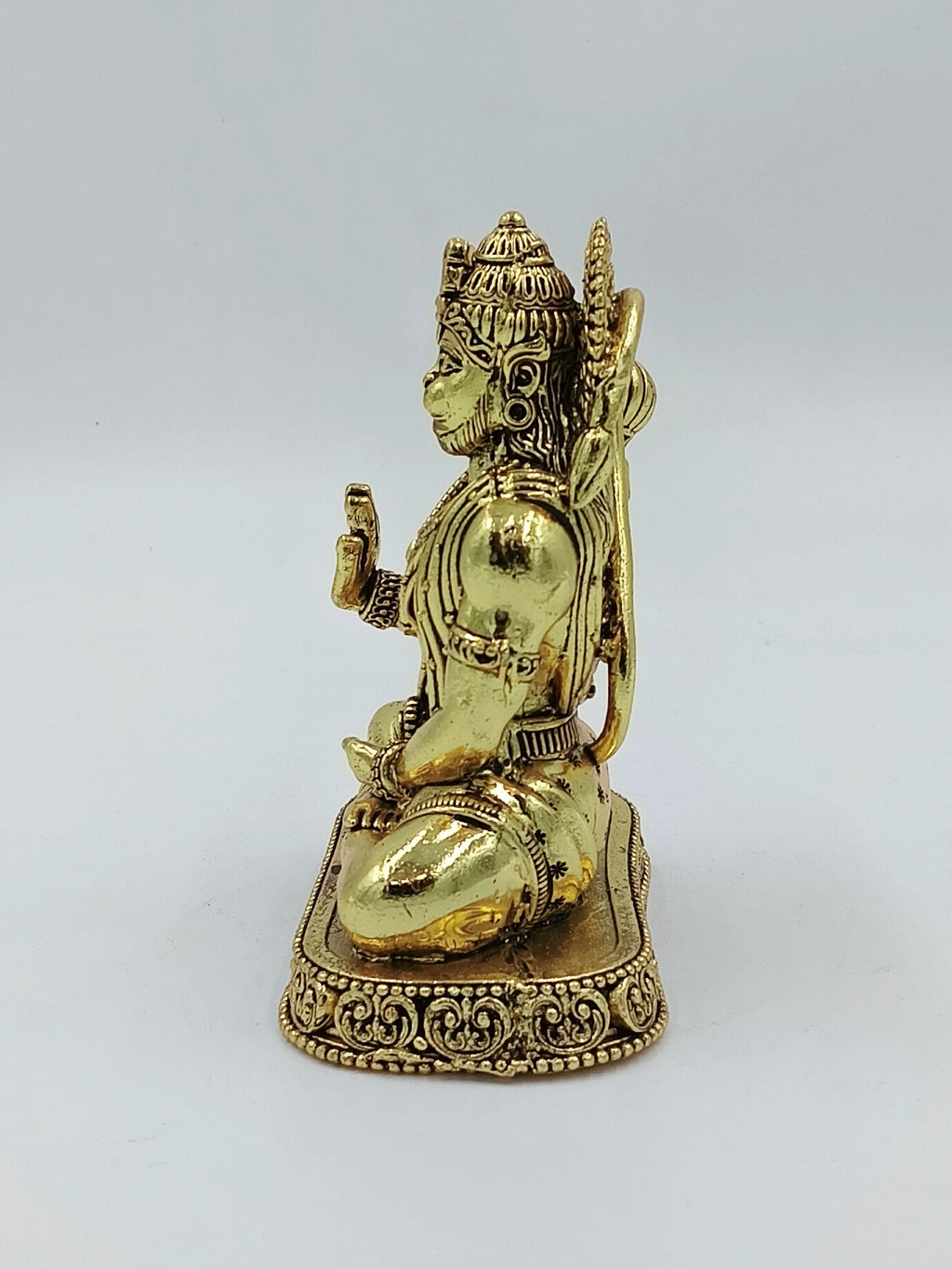 Side view of medium brass Hanuman sculpture seated on a decorative base
