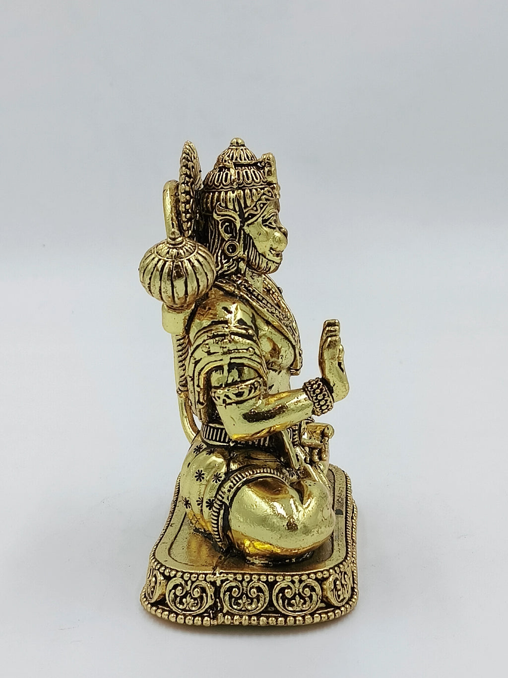 Side view of medium brass Hanuman statue sitting on decorated base