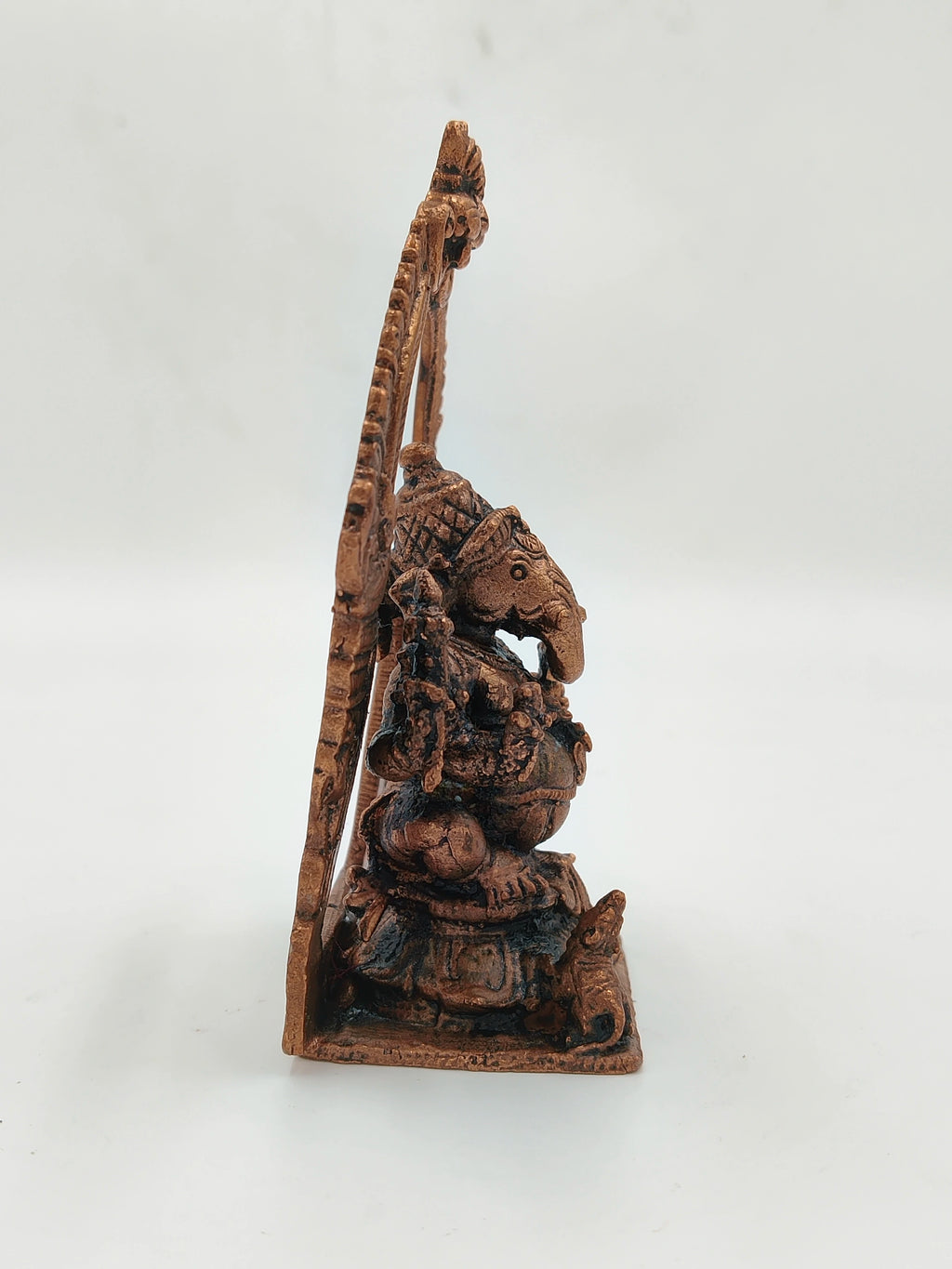 Side view of a small brass Ganesh statue with detailed carvings