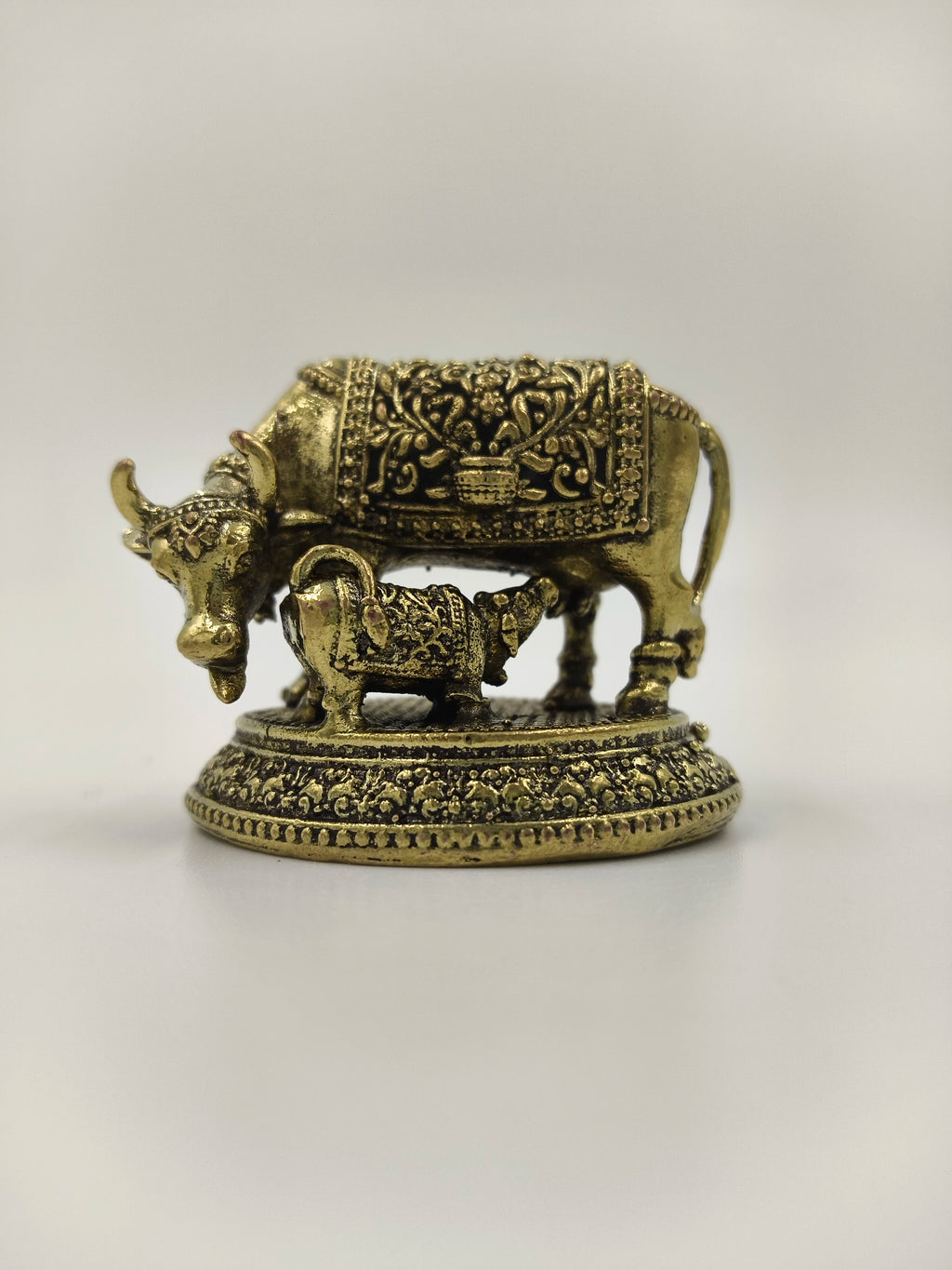 Mini brass sculpture of a cow and calf with detailed ornamental design