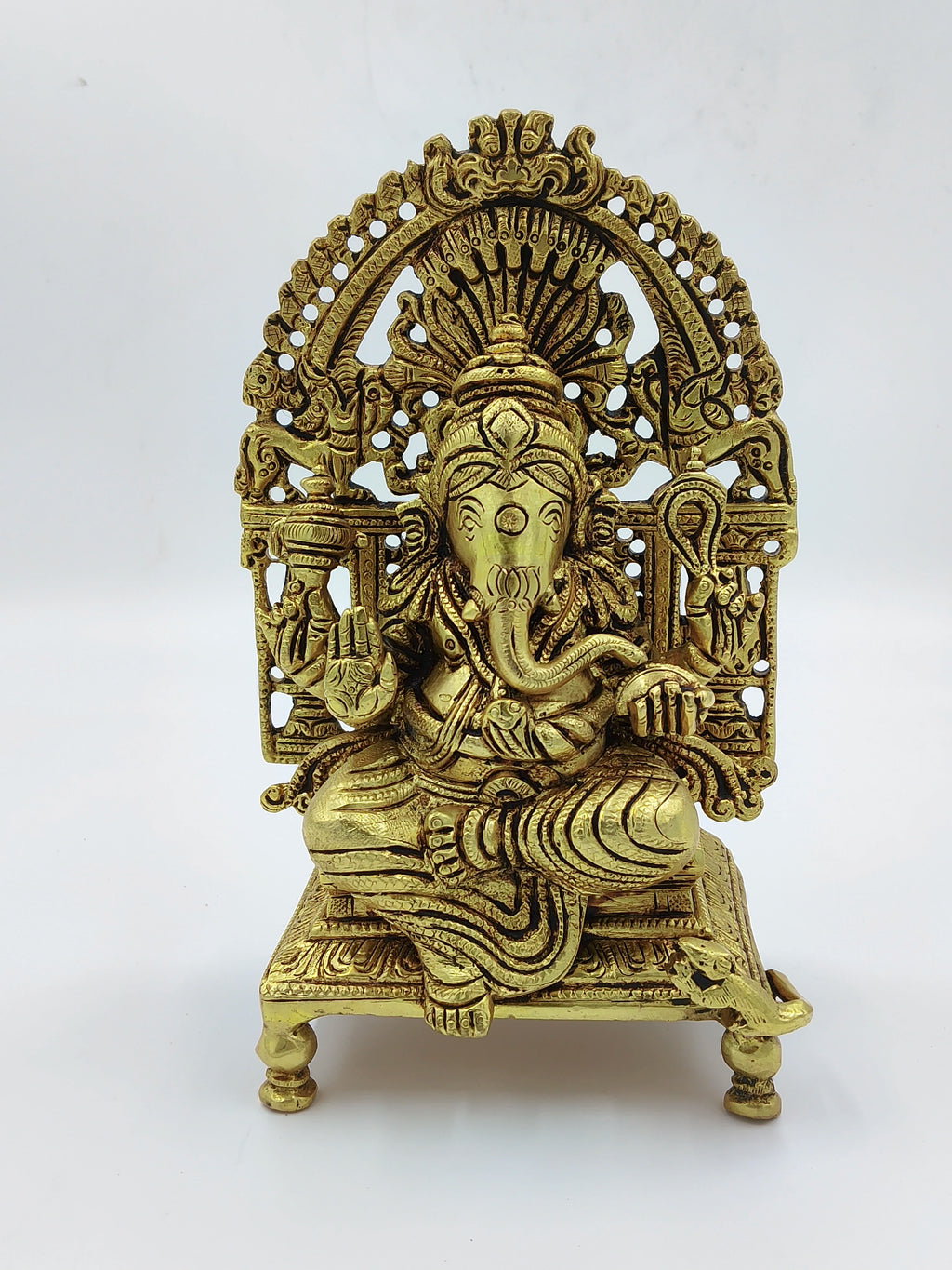 Large brass Ganesh statue seated with intricate carved backrest on platform