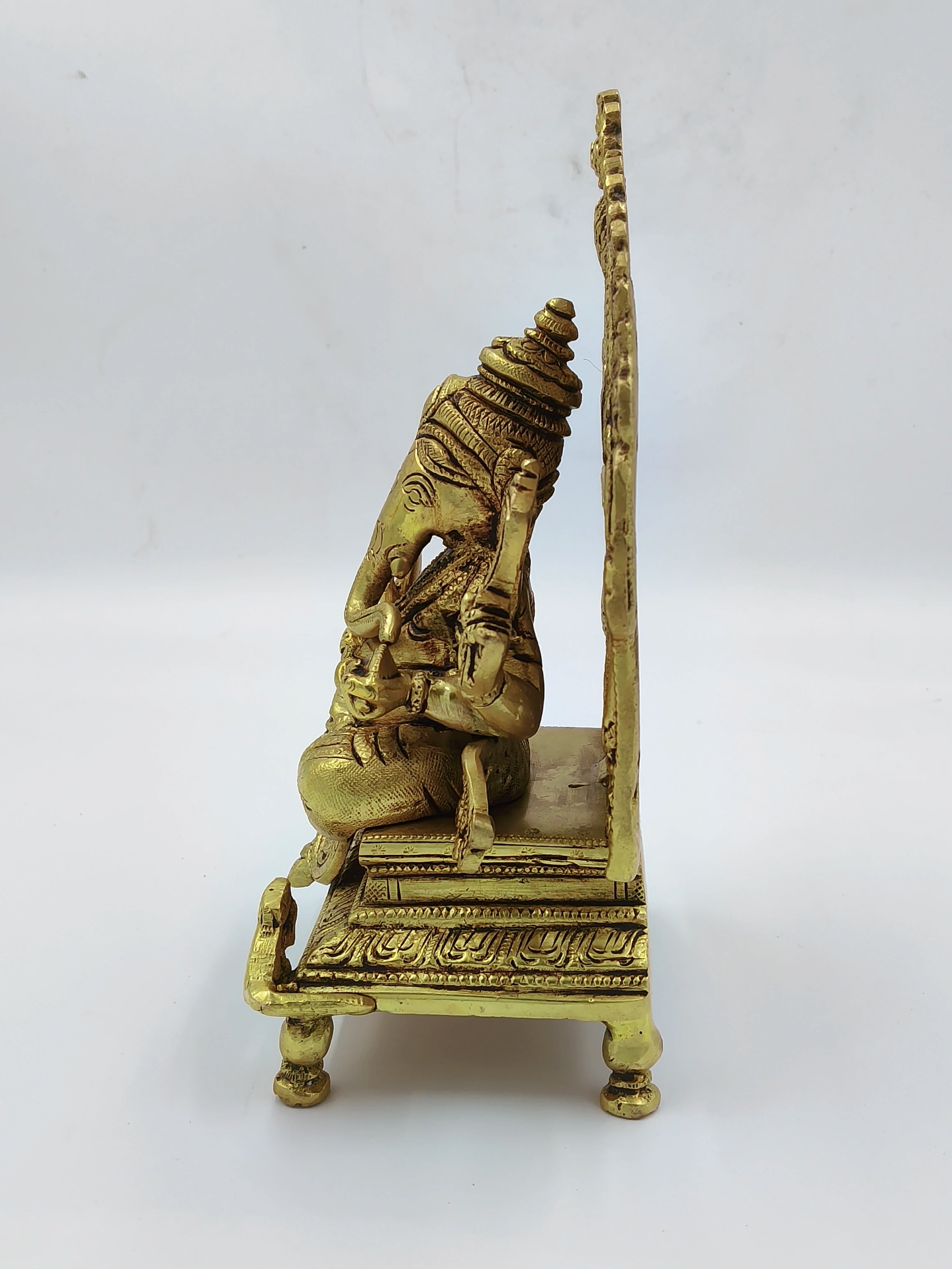 Side view of a large brass Ganesh statue sitting on a decorative throne
