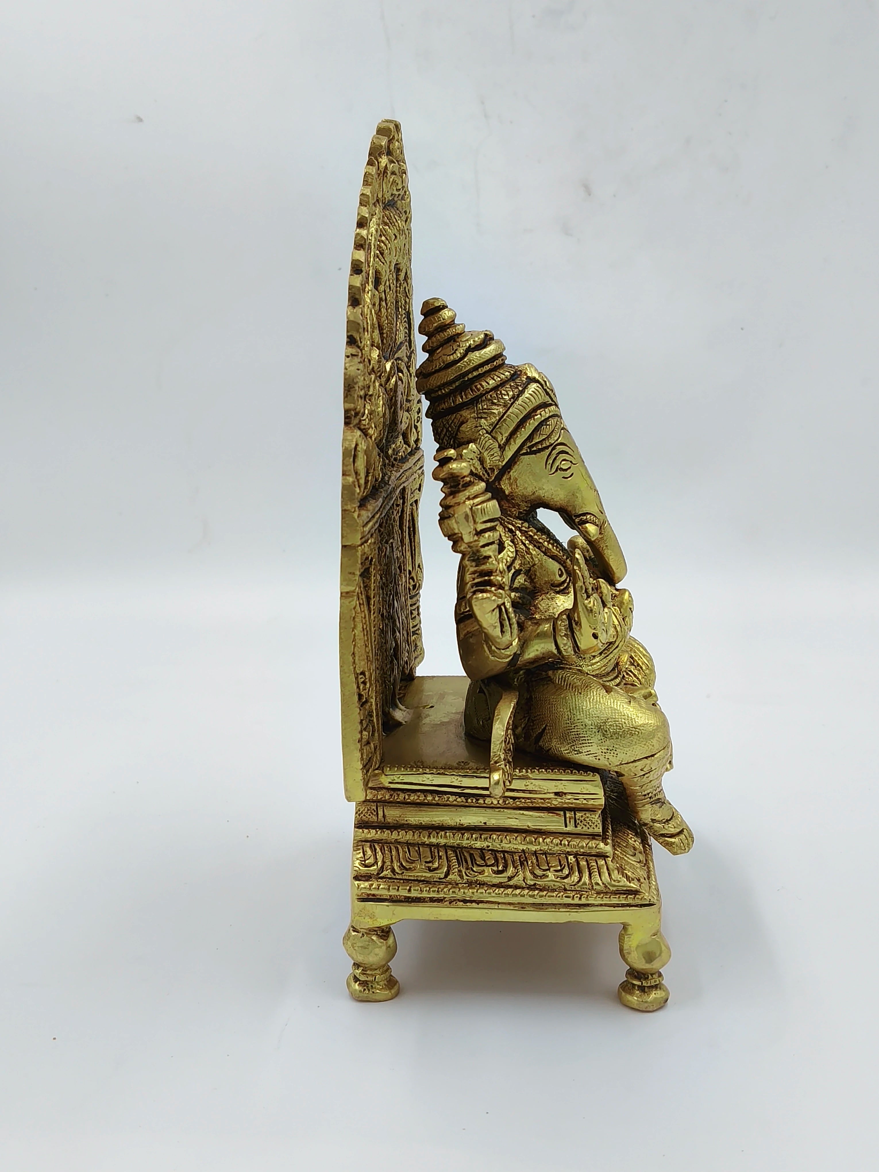 Side view of large brass Ganesh sculpture seated on ornate throne