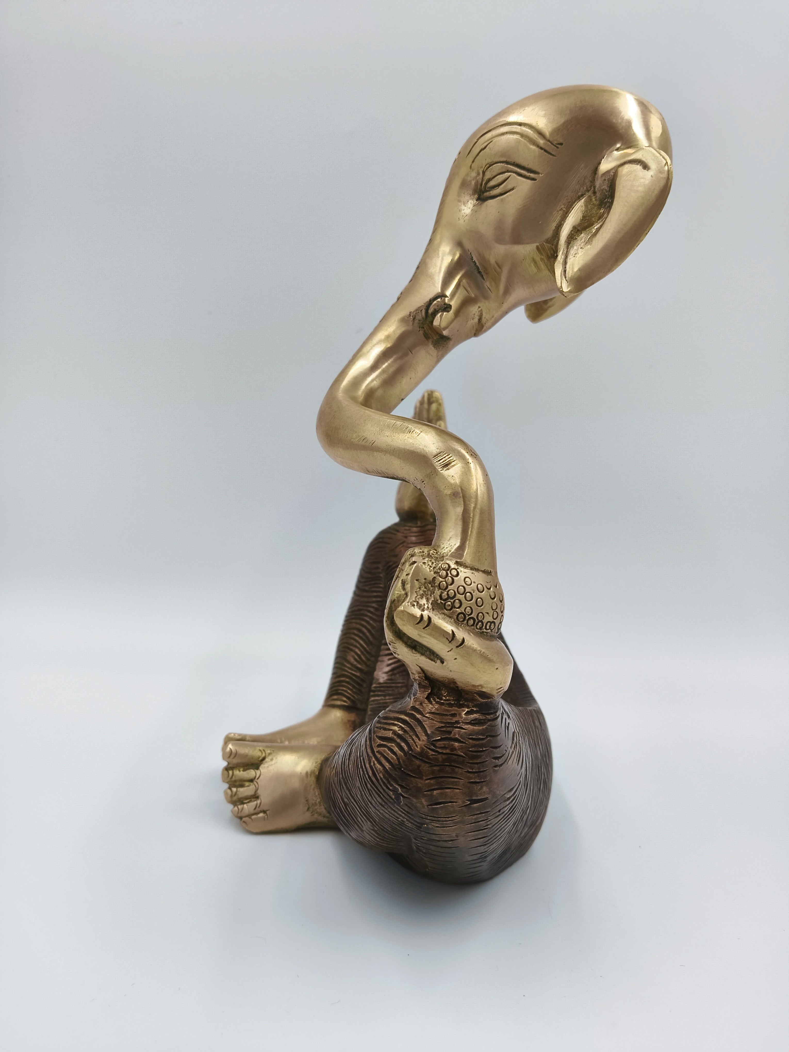 Modern brass Ganesha statue seated, side view with detailed texture