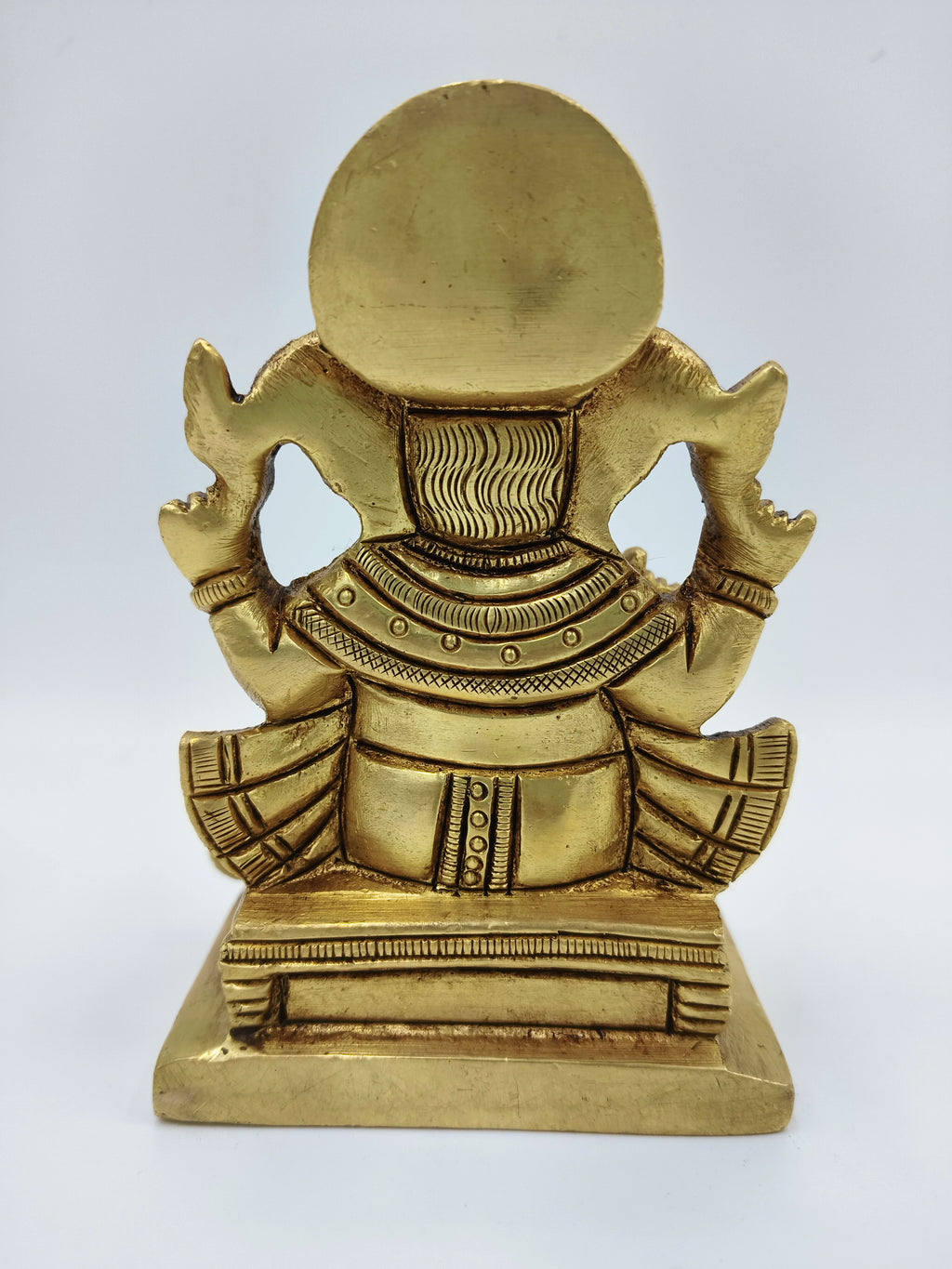 Back view of small brass statue of Lord Ganesha sitting on a pedestal