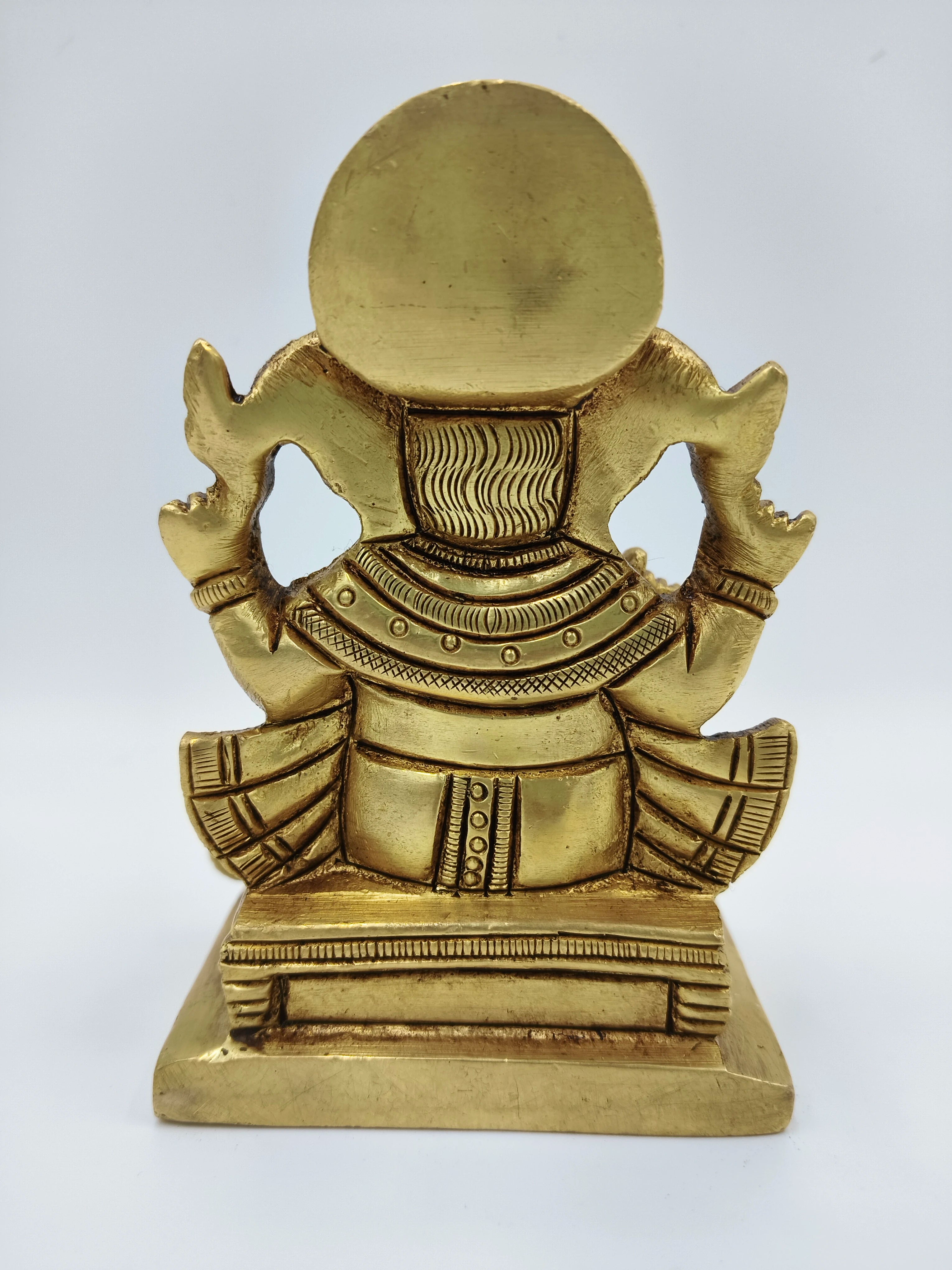 Back view of small brass statue of Lord Ganesha sitting on a pedestal