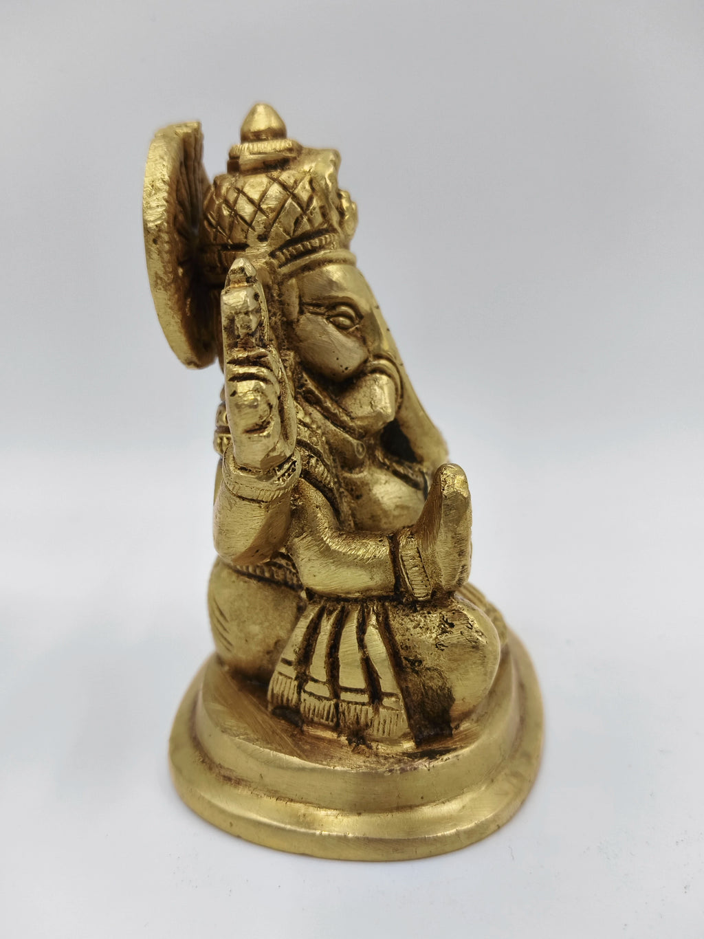 Small brass Ganesha statue sitting on round base side view