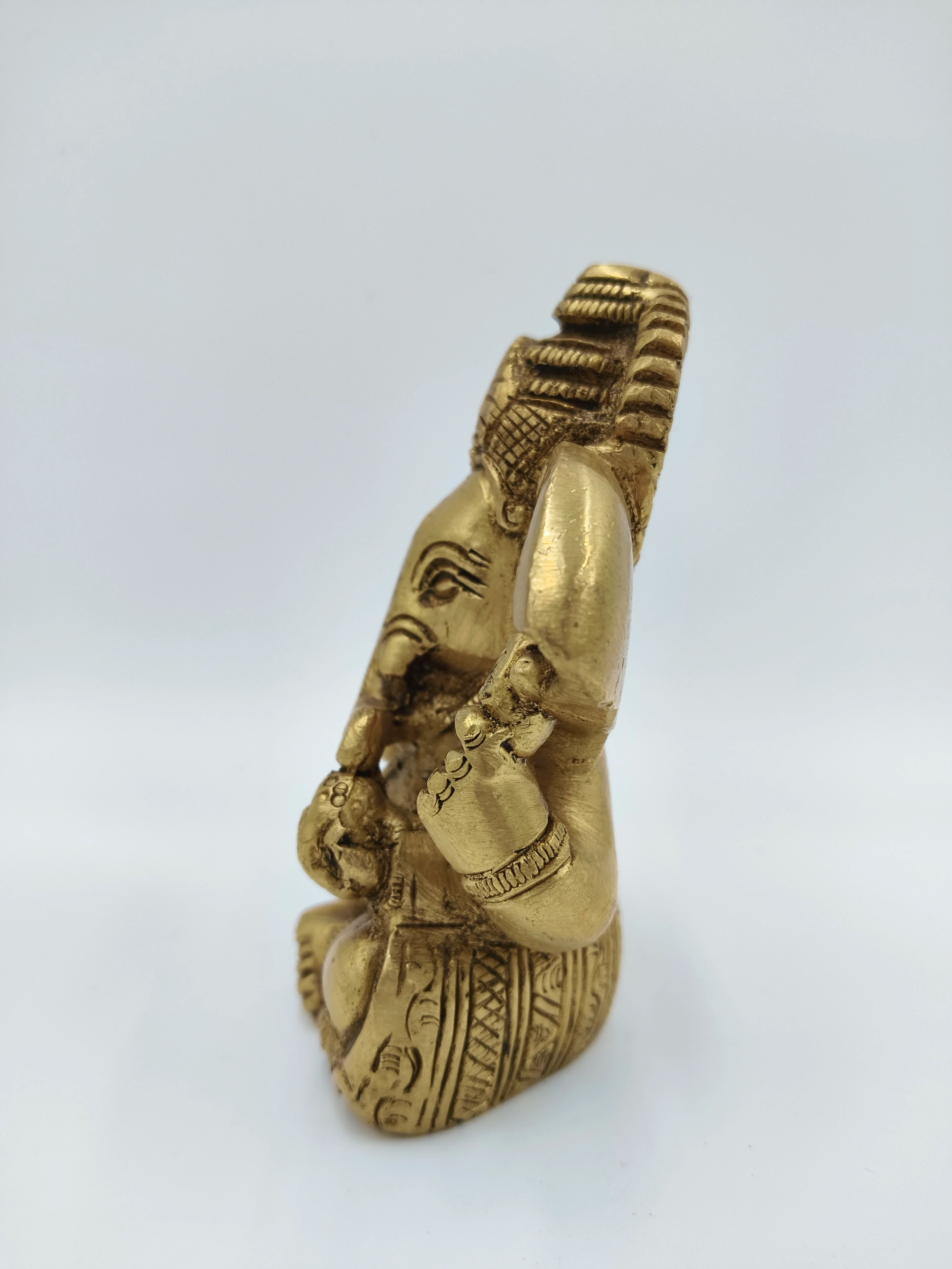 Side view of small brass Appu Ganesha statue with detailed carvings