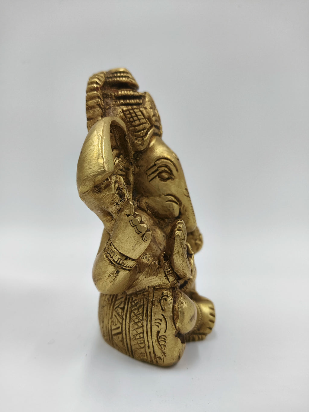 Side view of small brass Appu Ganesha statue with intricate carvings