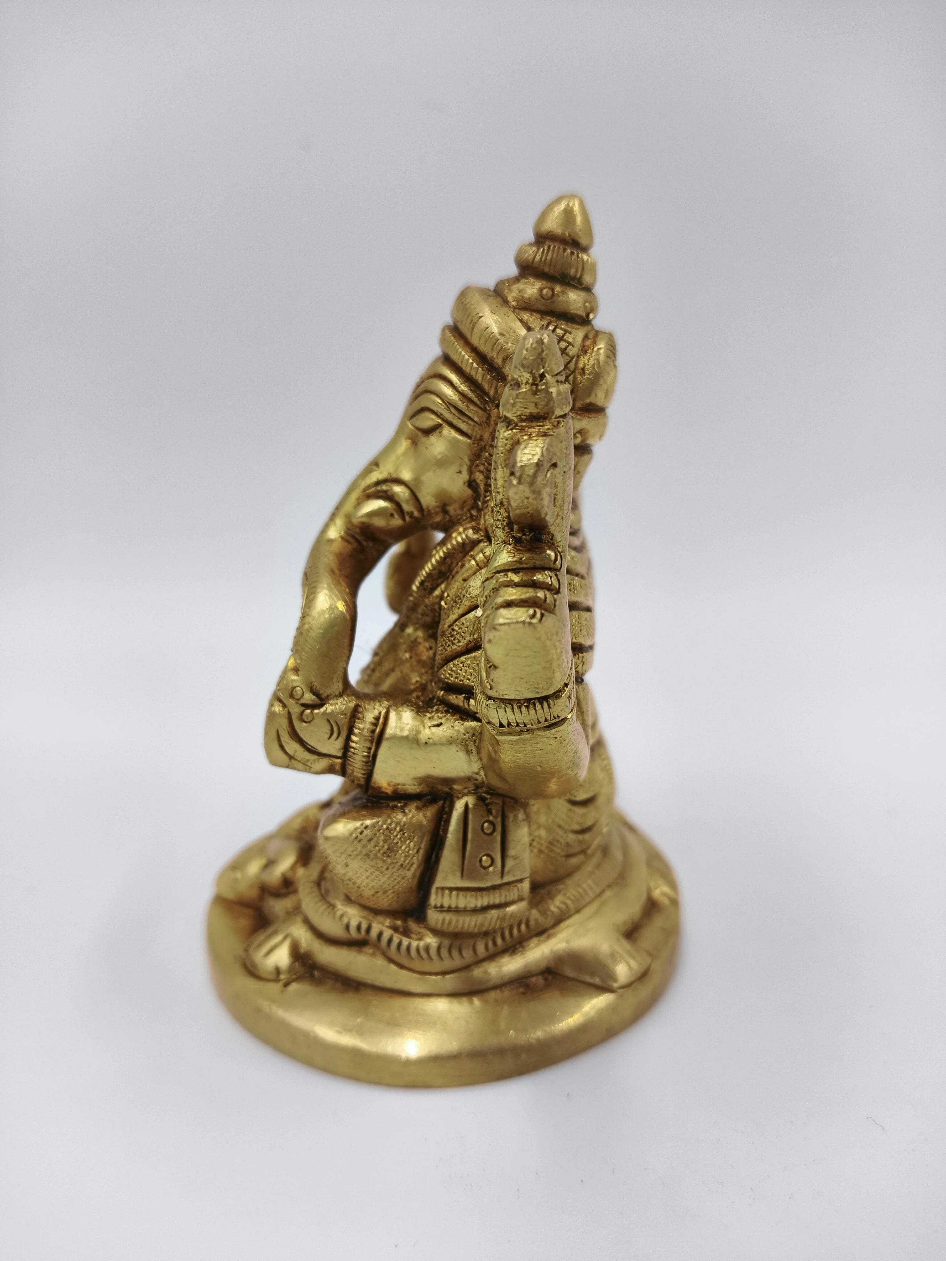 Small brass statue of sitting Lord Ganesha with detailed carvings, side view