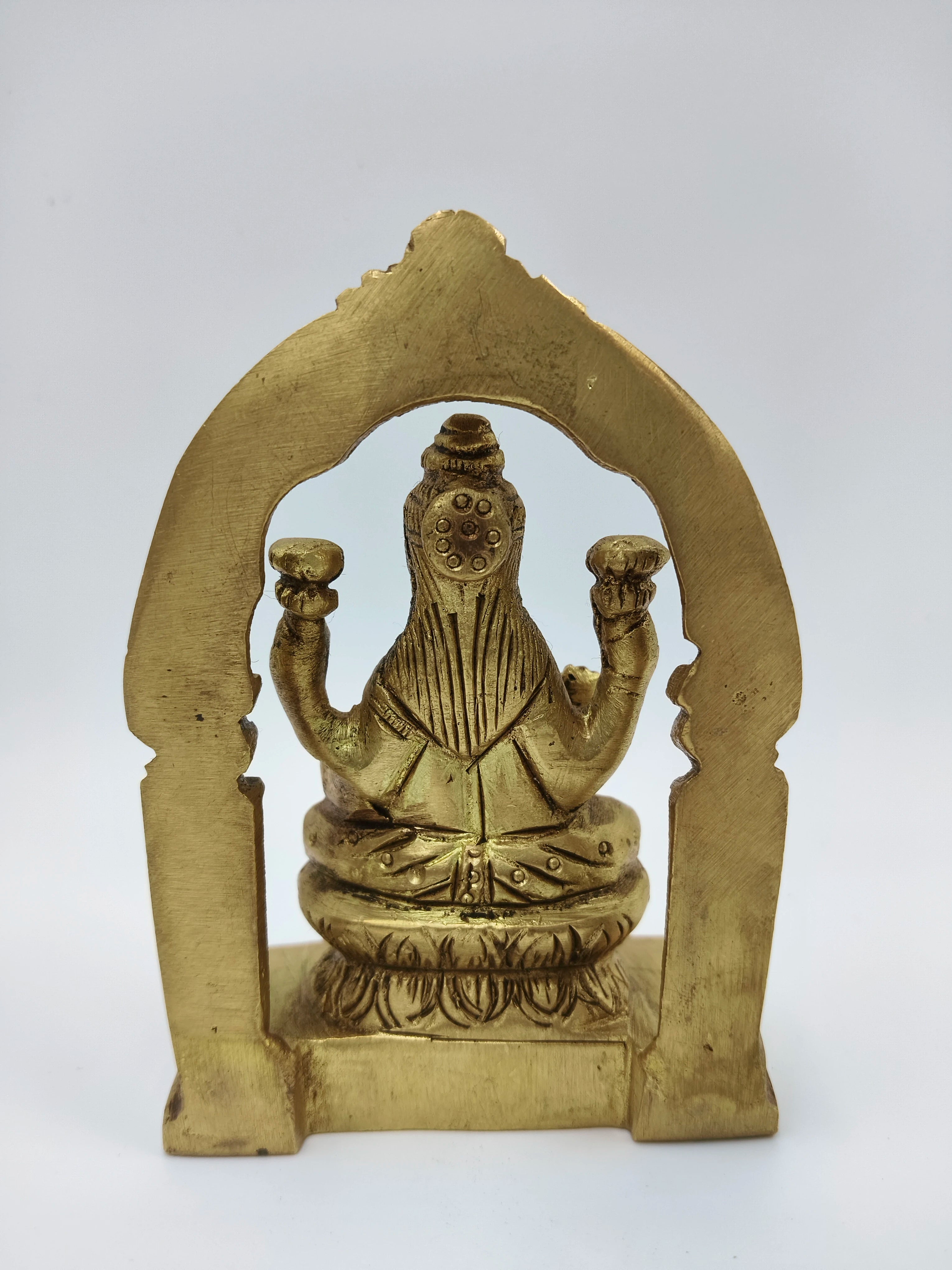 Back view of small brass statue of Goddess Lakshmi seated on lotus with arch frame