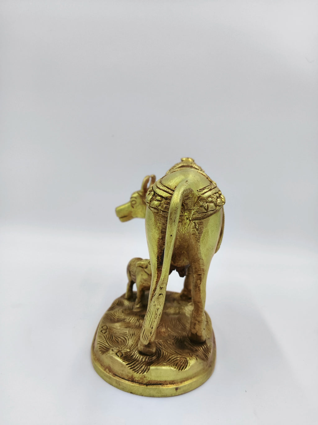 Rear view of large brass cow and calf sculpture with flower detailing