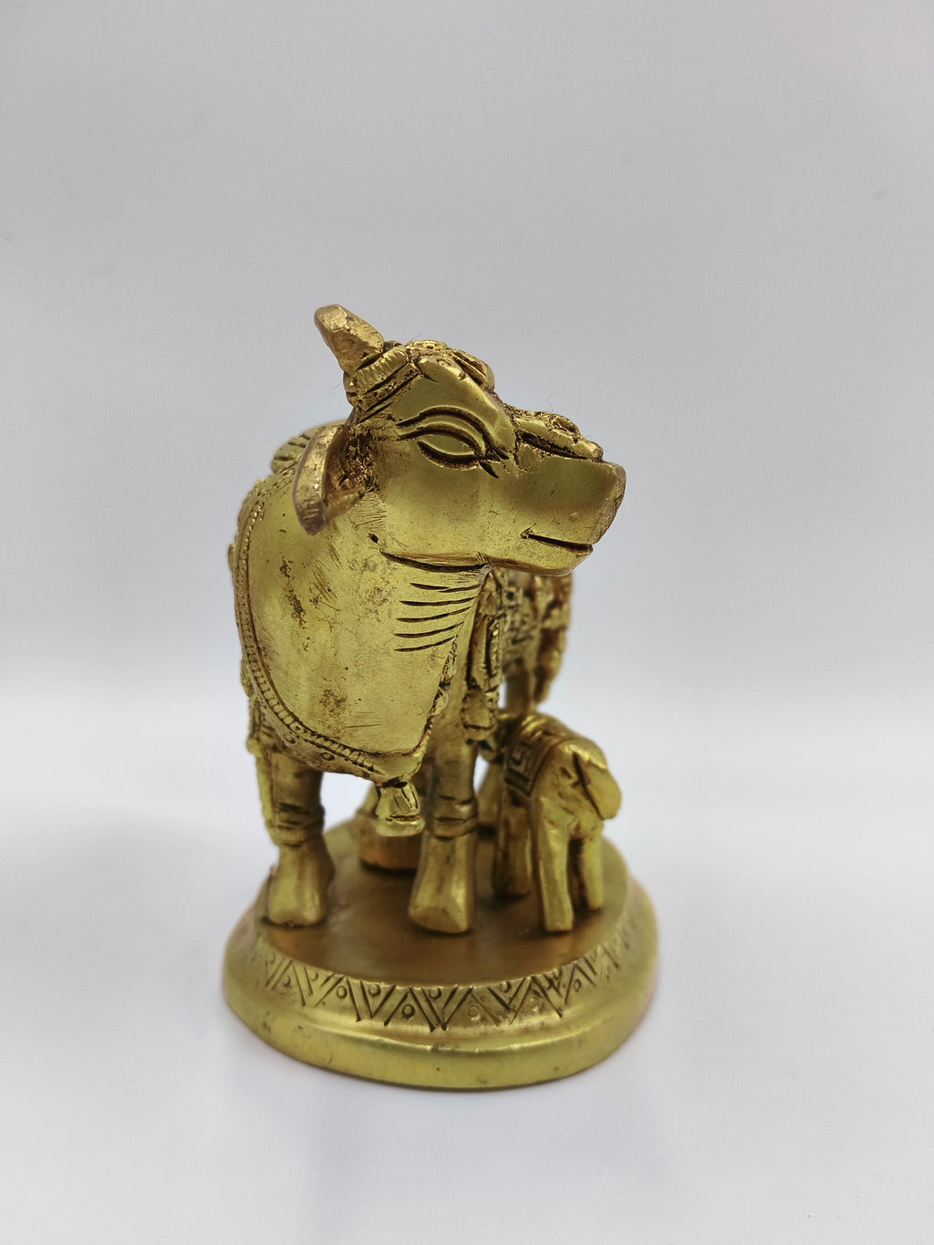 Small brass sculpture of a cow and calf with a divine figure on a round base